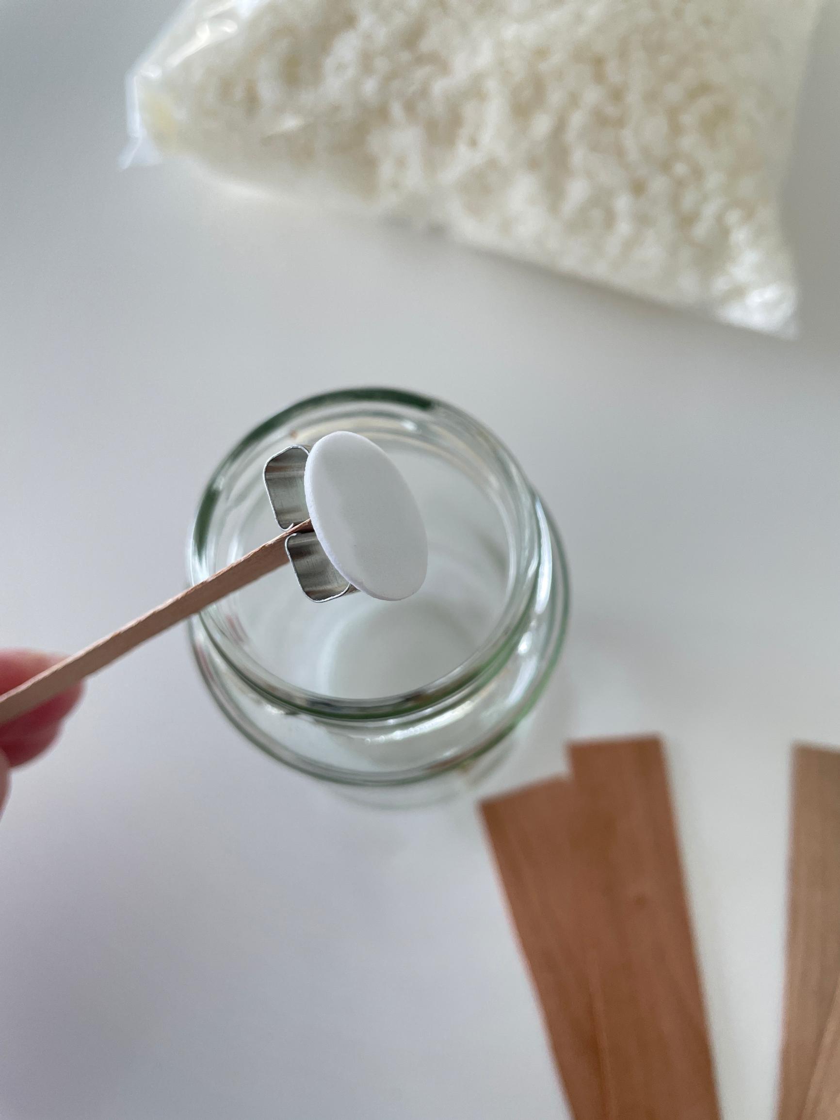 Attaching the wood wick to the bottom of the container