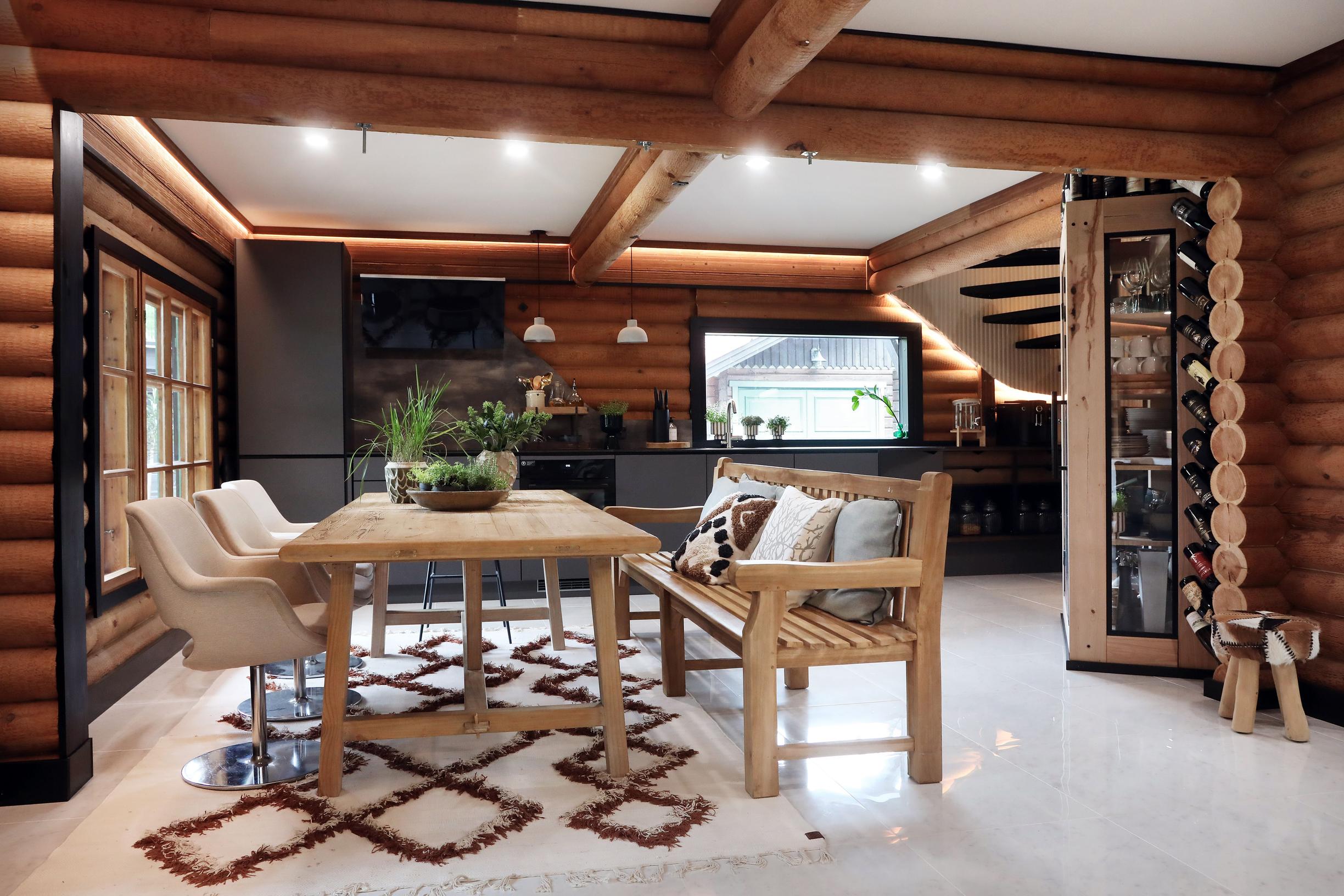 The kitchen features gray cabinetry and a wooden dining table. A wooden bench lines one side of the table.