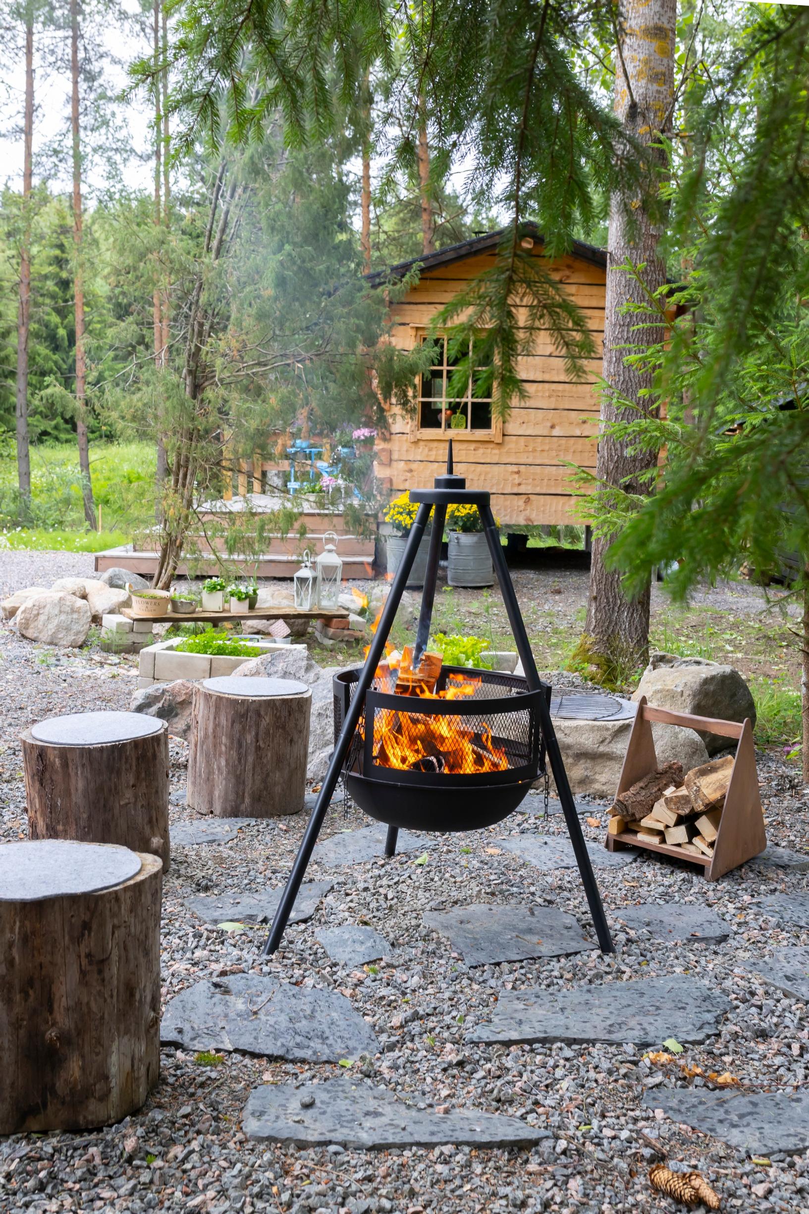 flagstones, a lit fire pit with logs, and a log cabin in the background