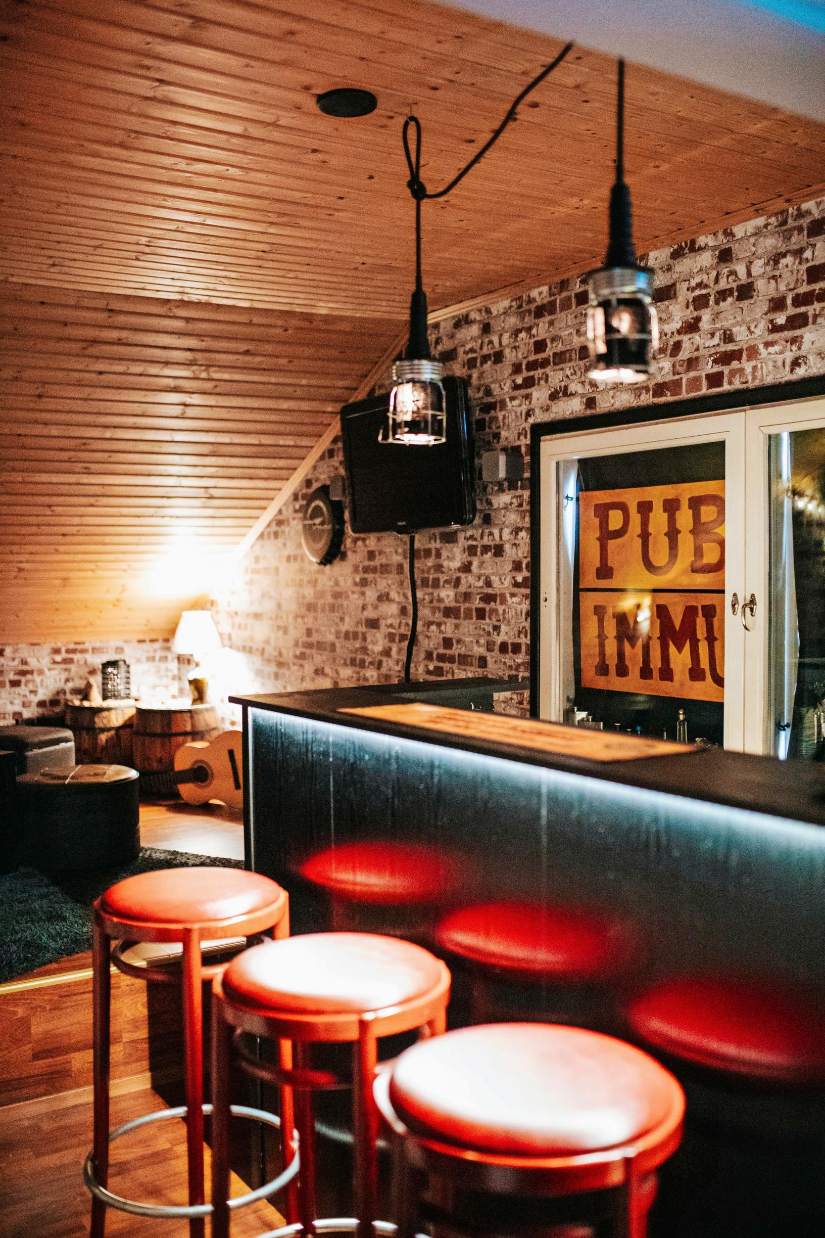 bar counter, bar stools, and a brick-style wall in the background