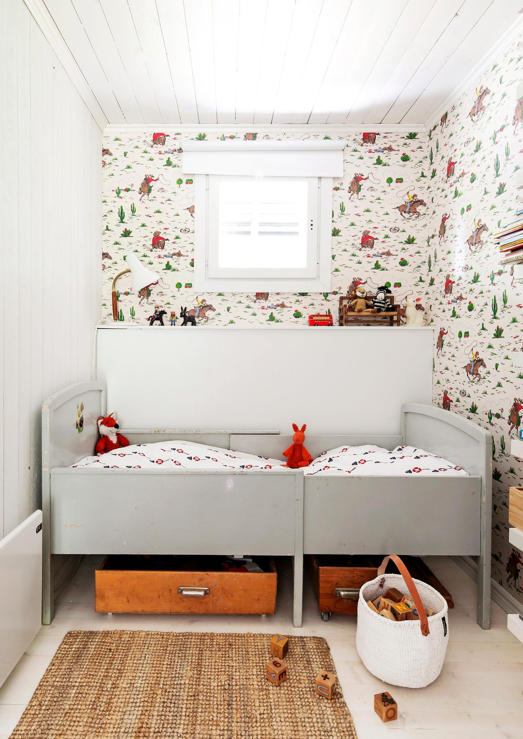 A children’s room bed with rolling toy boxes underneath.