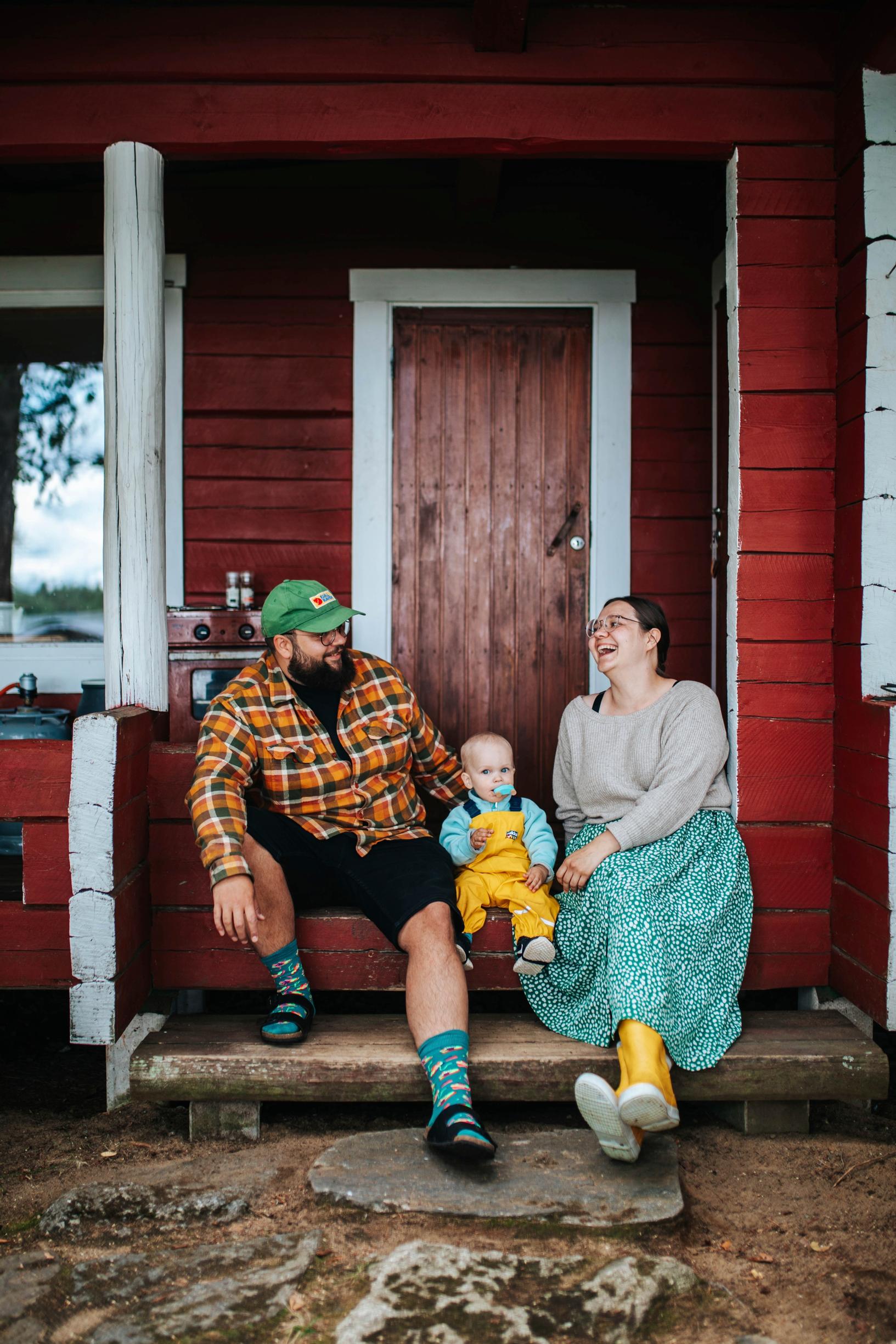 A father, mother, and toddler on the cottage steps.