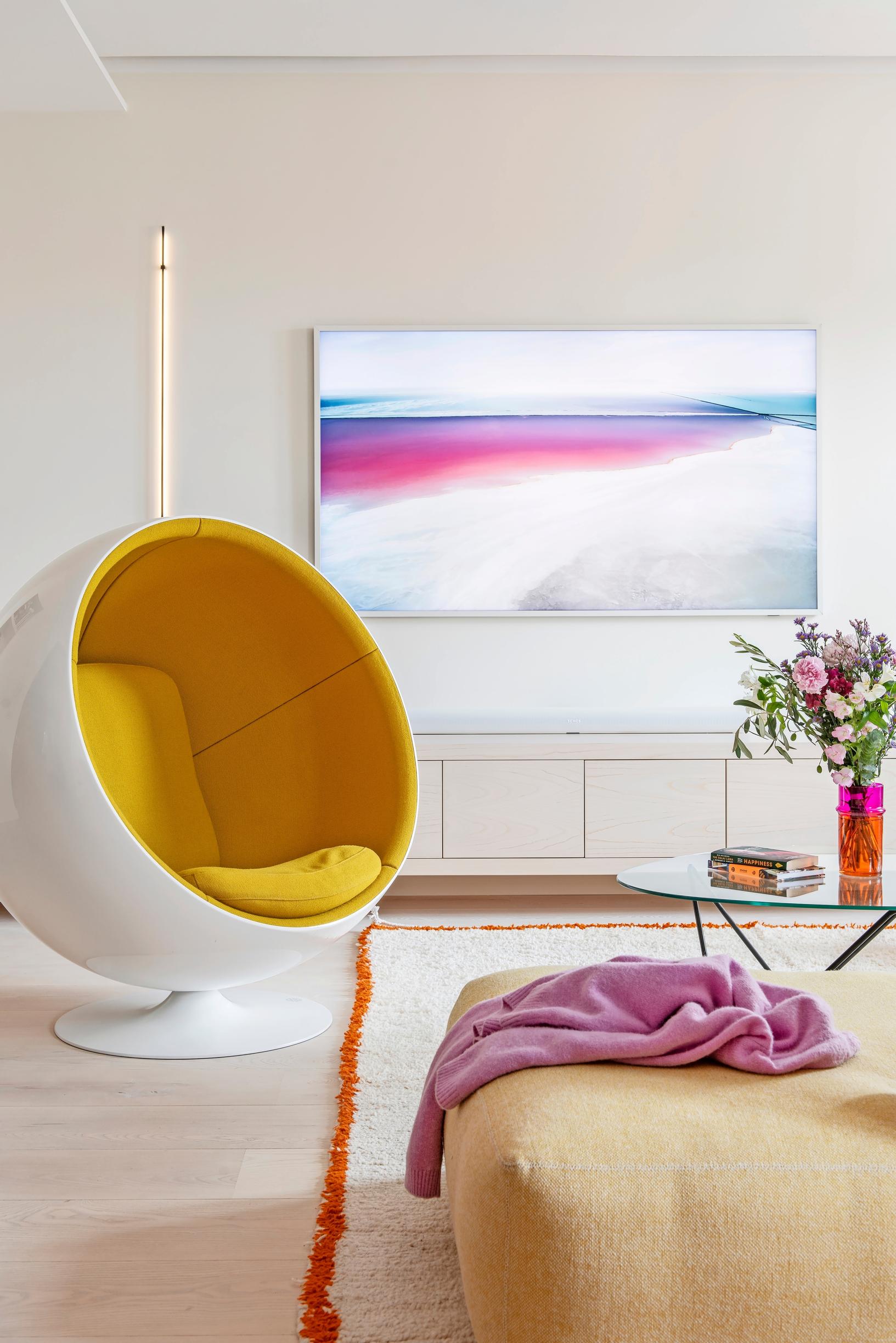 The Ball Chair designed by Eero Aarnio, a TV stand, and a large flat-screen TV in the living room