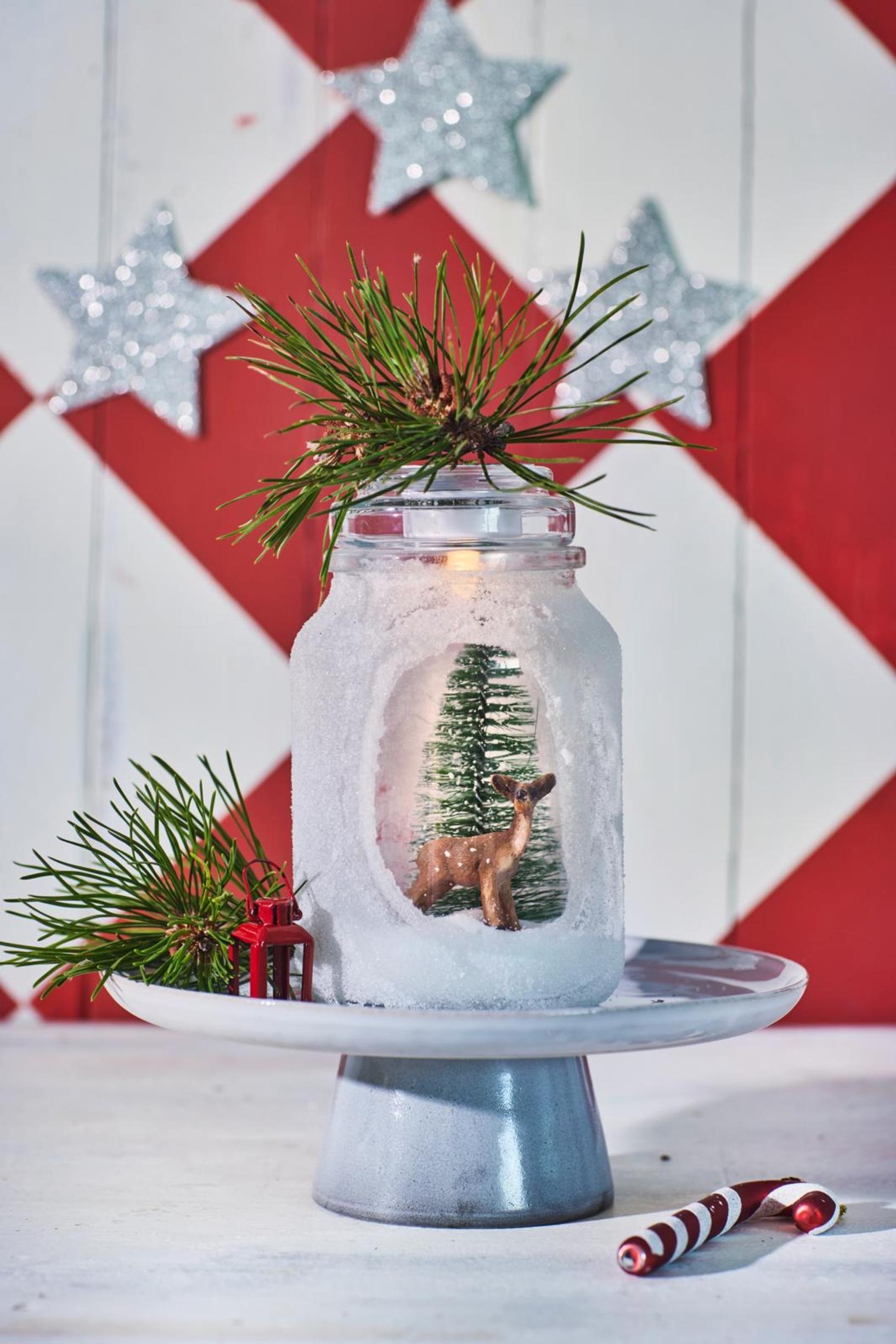 Use a brush to spread glue all around the jar, but leave an oval peek-through window bare. Roll the jar in sugar or salt. Place the decorations you want inside and pour in sugar or salt for snow.