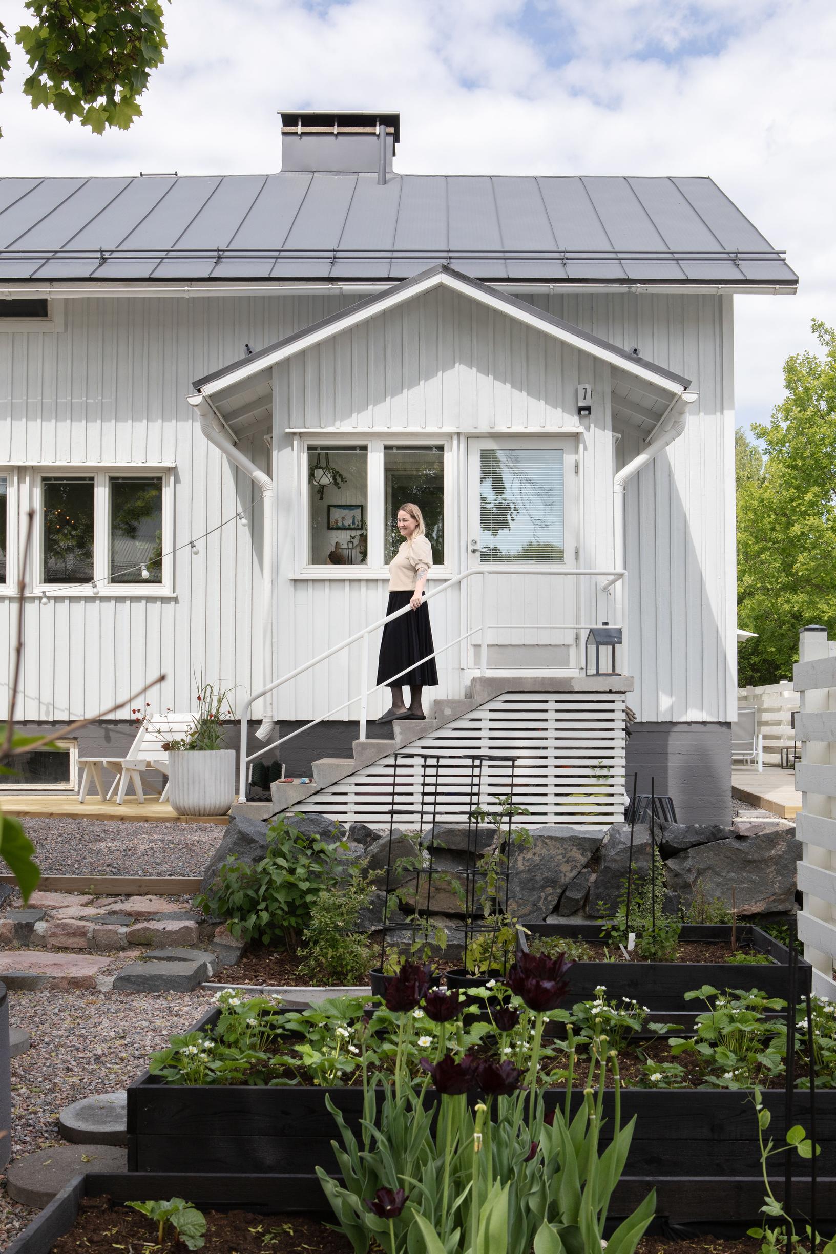Outi on the porch of her single-family home, with planter boxes in the foreground.
