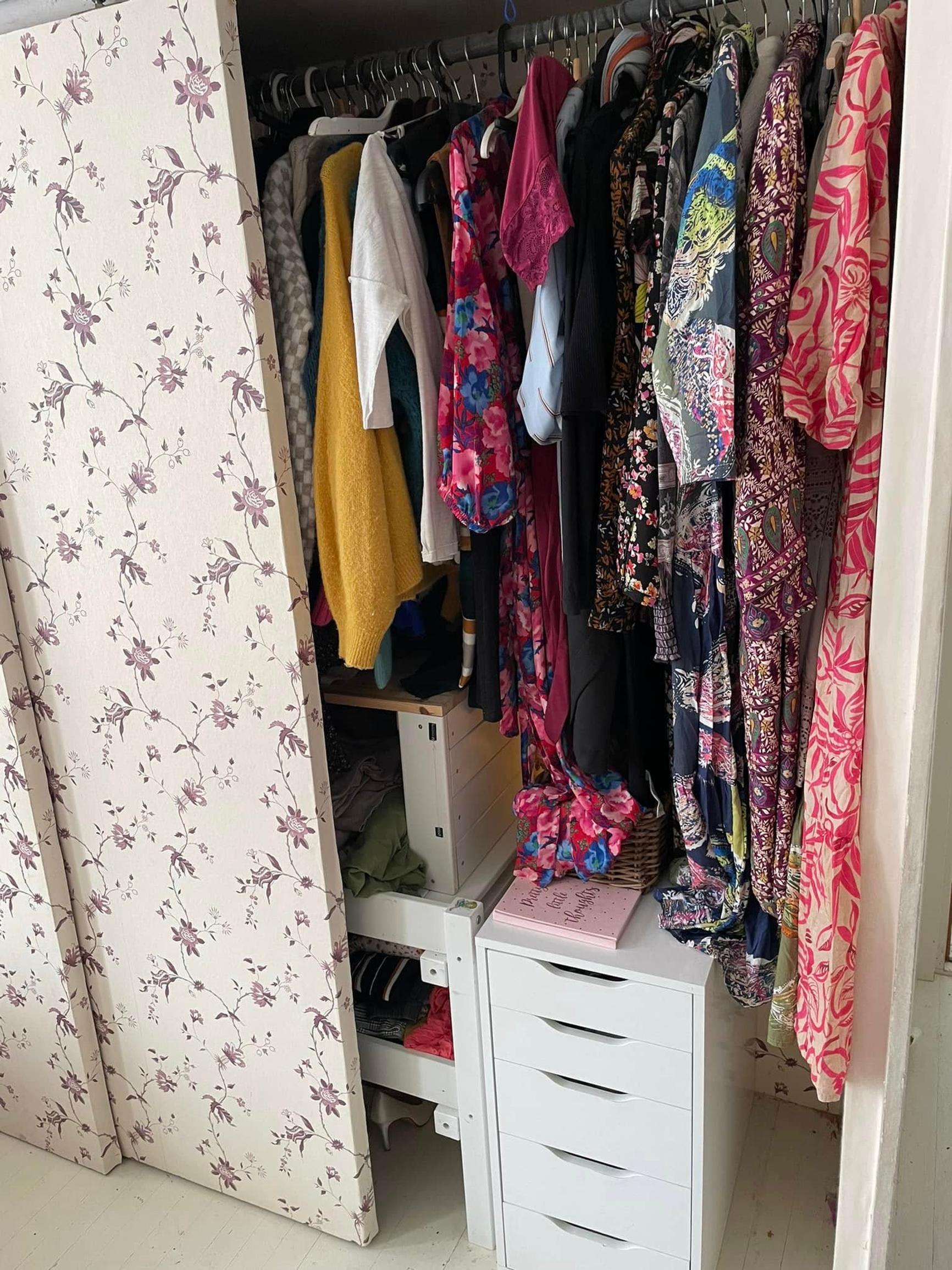 The sliding-door closet is half open, showing clothes hanging inside.
