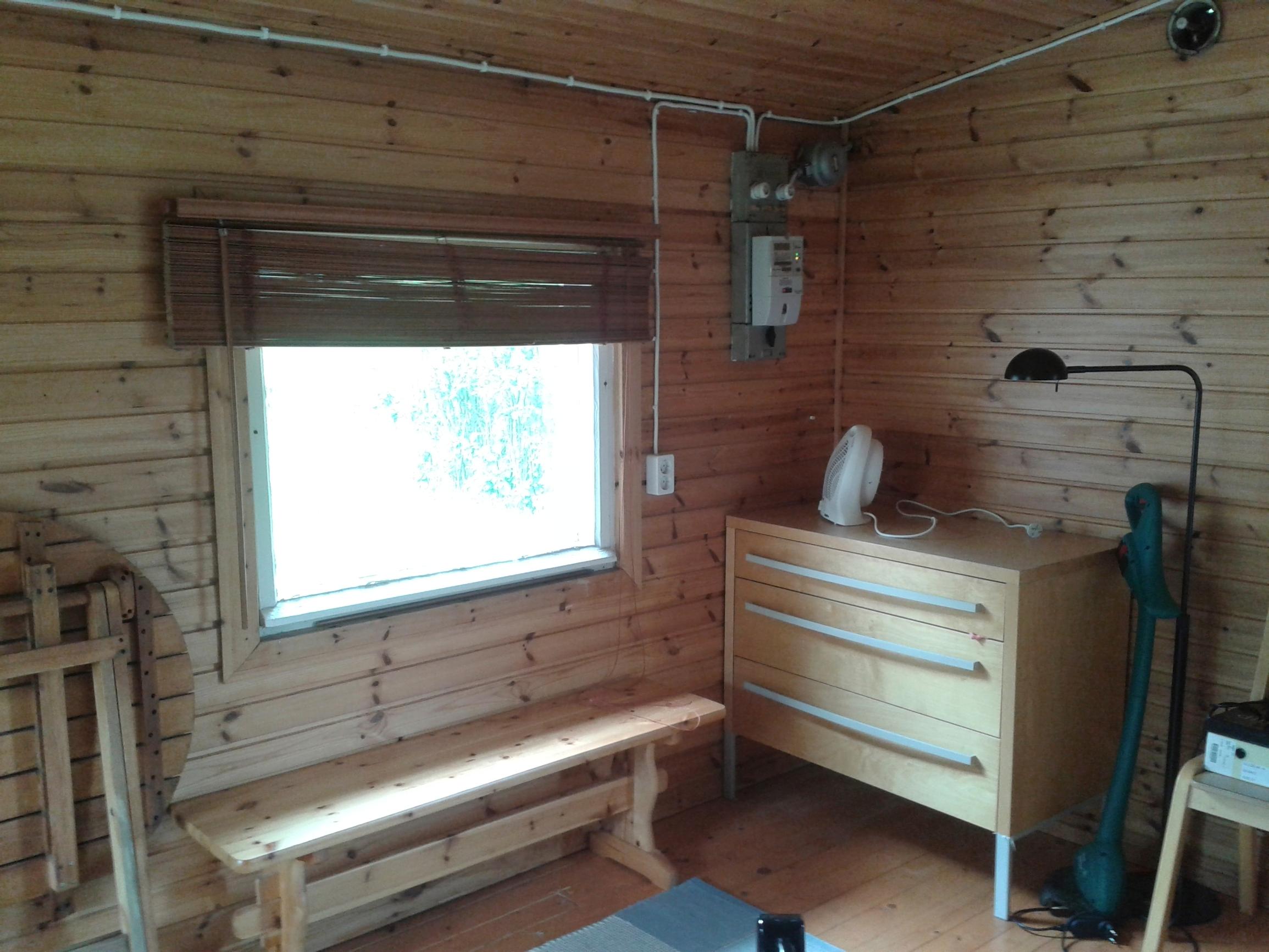 a wooden bench and bureau near a window in a dimly lit cottage