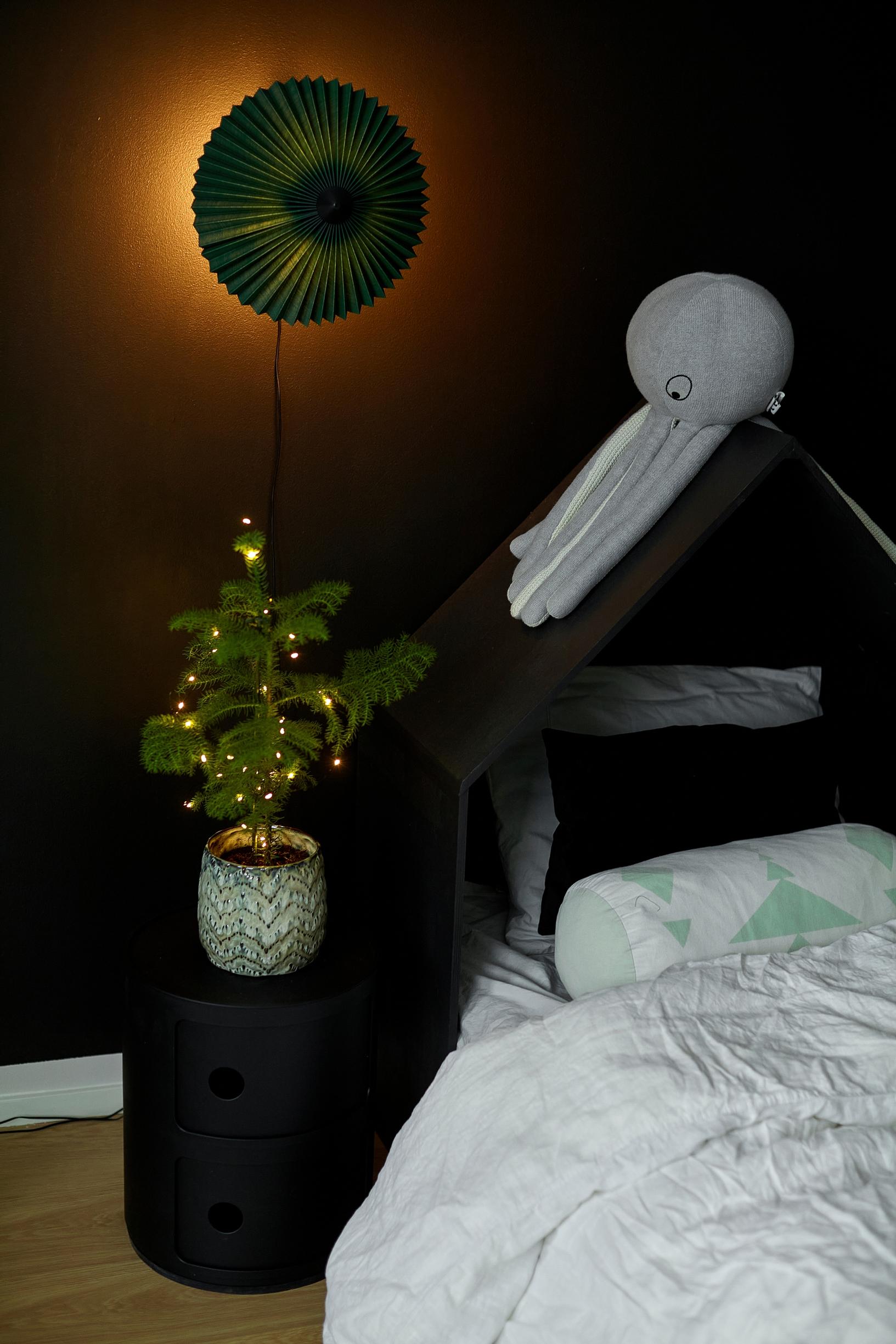 a small Christmas tree on a nightstand and a bed