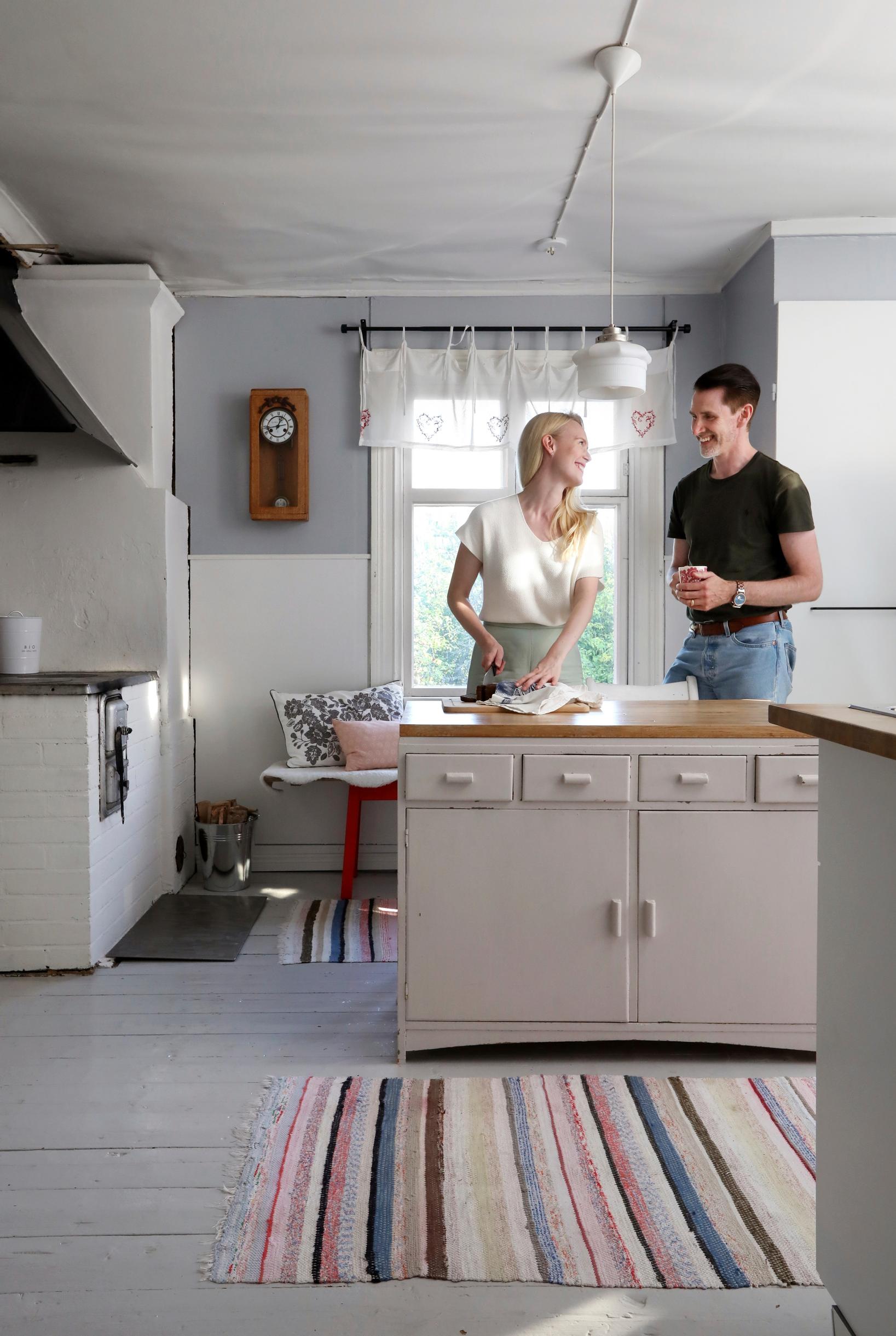 Jutta and Sami Helenius by the kitchen island, plank floor, and rag rug
