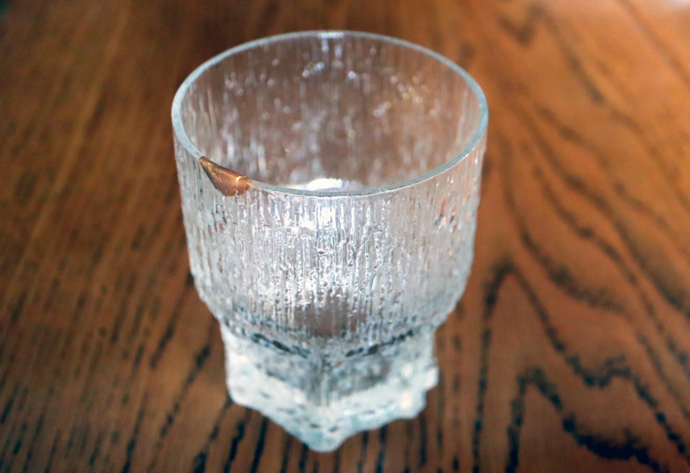 A drinking glass repaired with the kintsugi technique on a table.