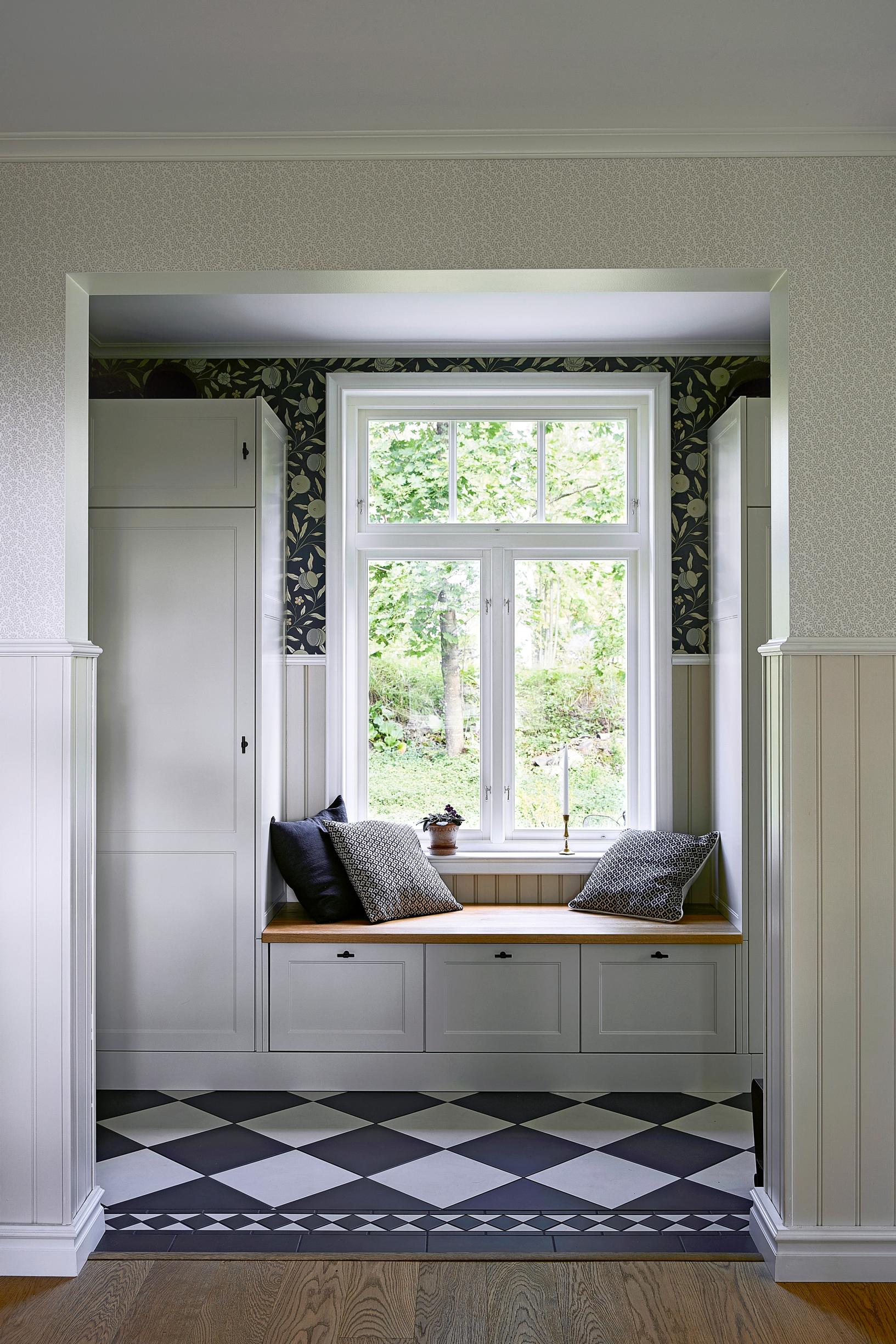 Built-in bench with drawers between cabinets under the entryway window