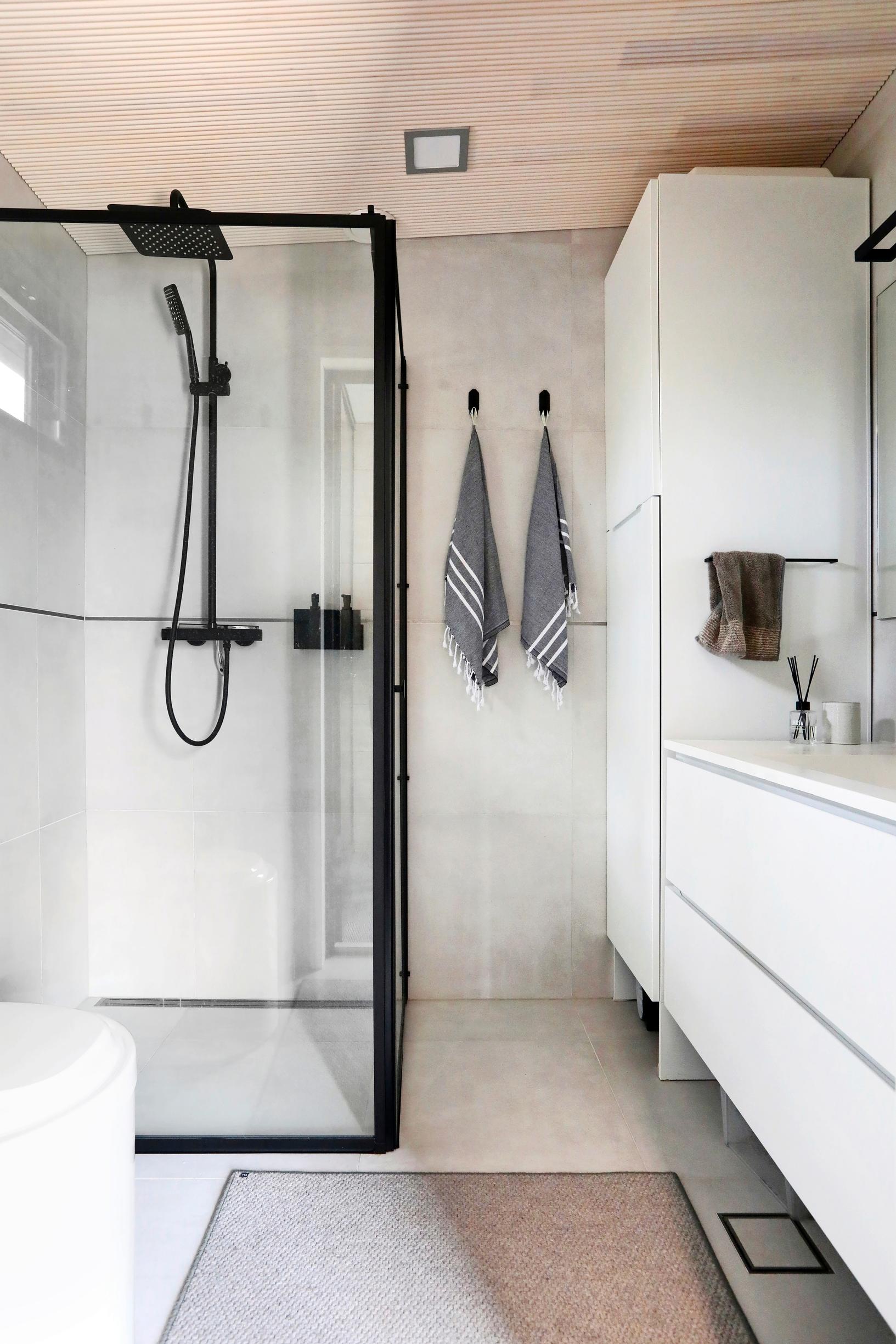 A black-framed shower enclosure adds a lively edge to the white bathroom.