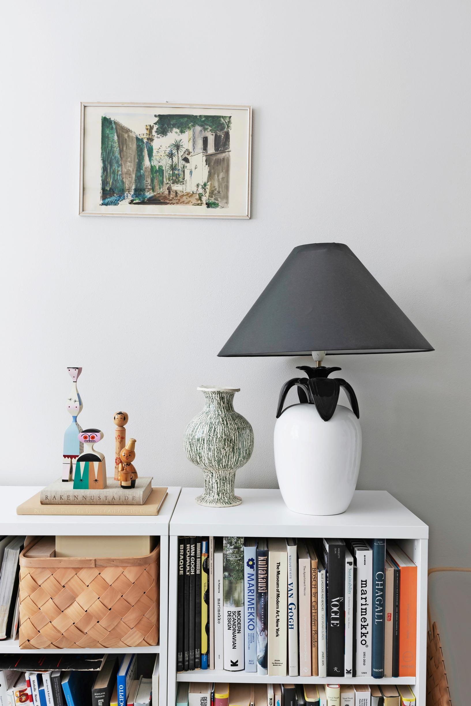 An 80s-style lamp and wooden figures on a low bookshelf