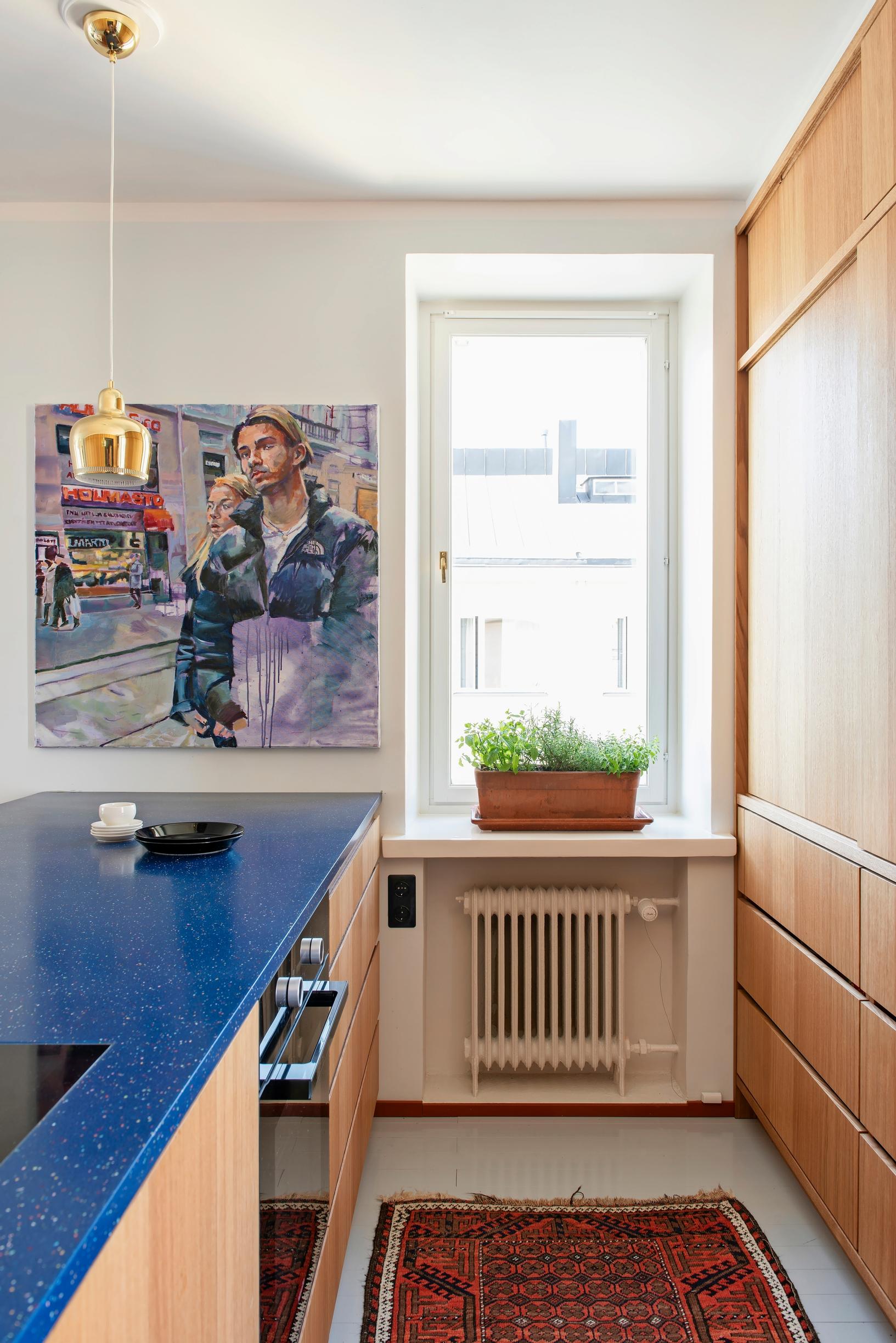 In the spacious open kitchen, a painting and a blue Durat countertop on the island.