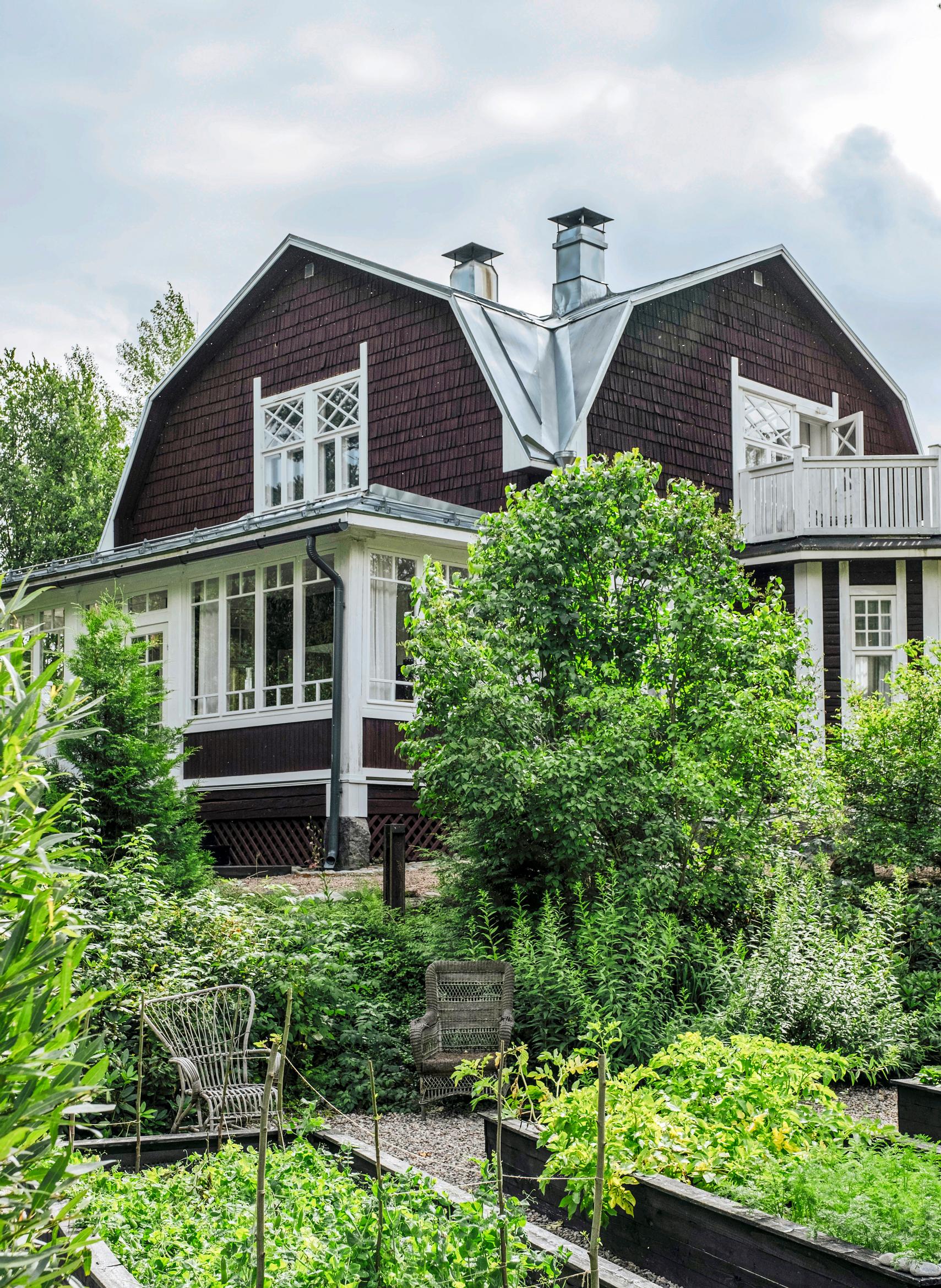 House in the background. Raised beds and garden in front.