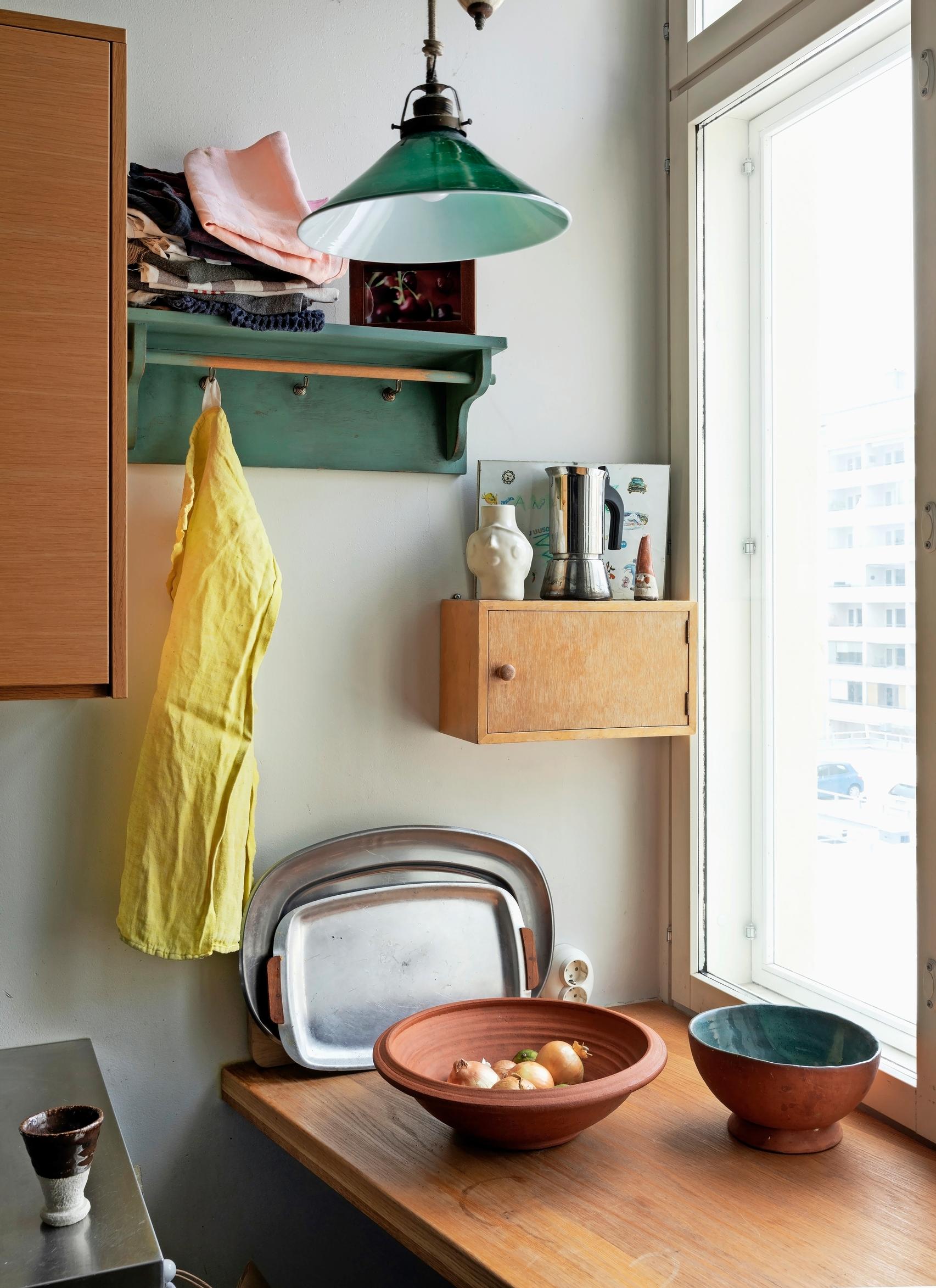 A wall-mounted cabinet, a shelf, and a counter holding two bowls and vintage platters.