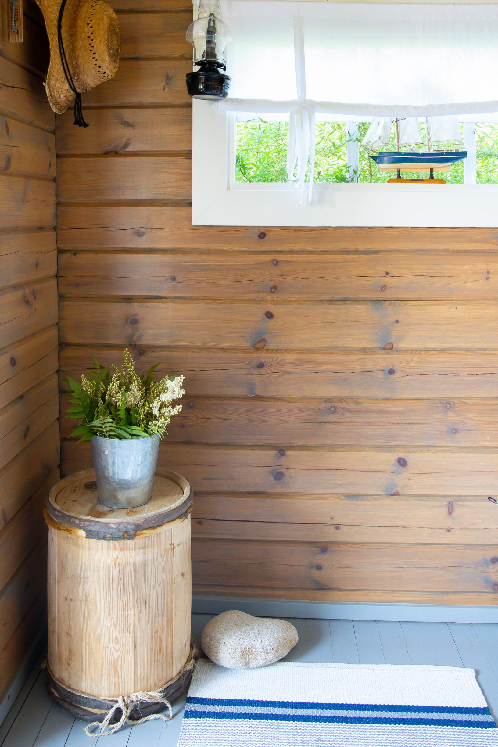 an old wooden barrel on the floor by a wooden wall, with a rug