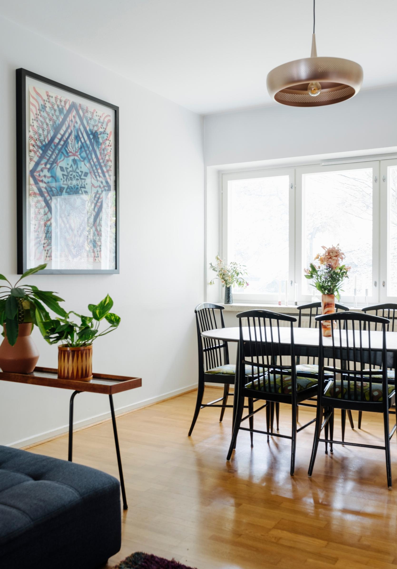 A dining set featuring black chairs beside a delicate vintage plant stand