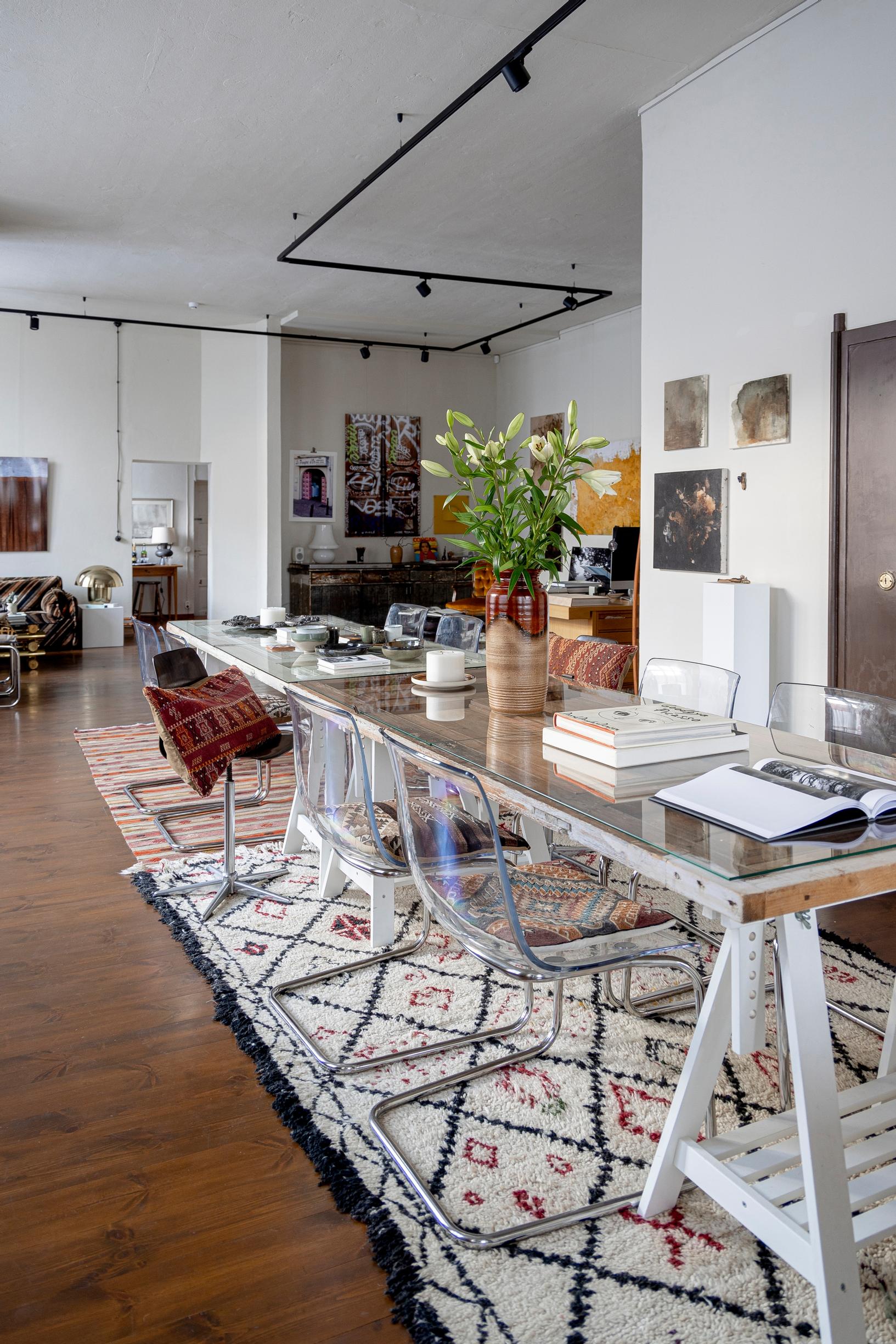 A trestle table and transparent plastic chairs on top of a vintage wool rug