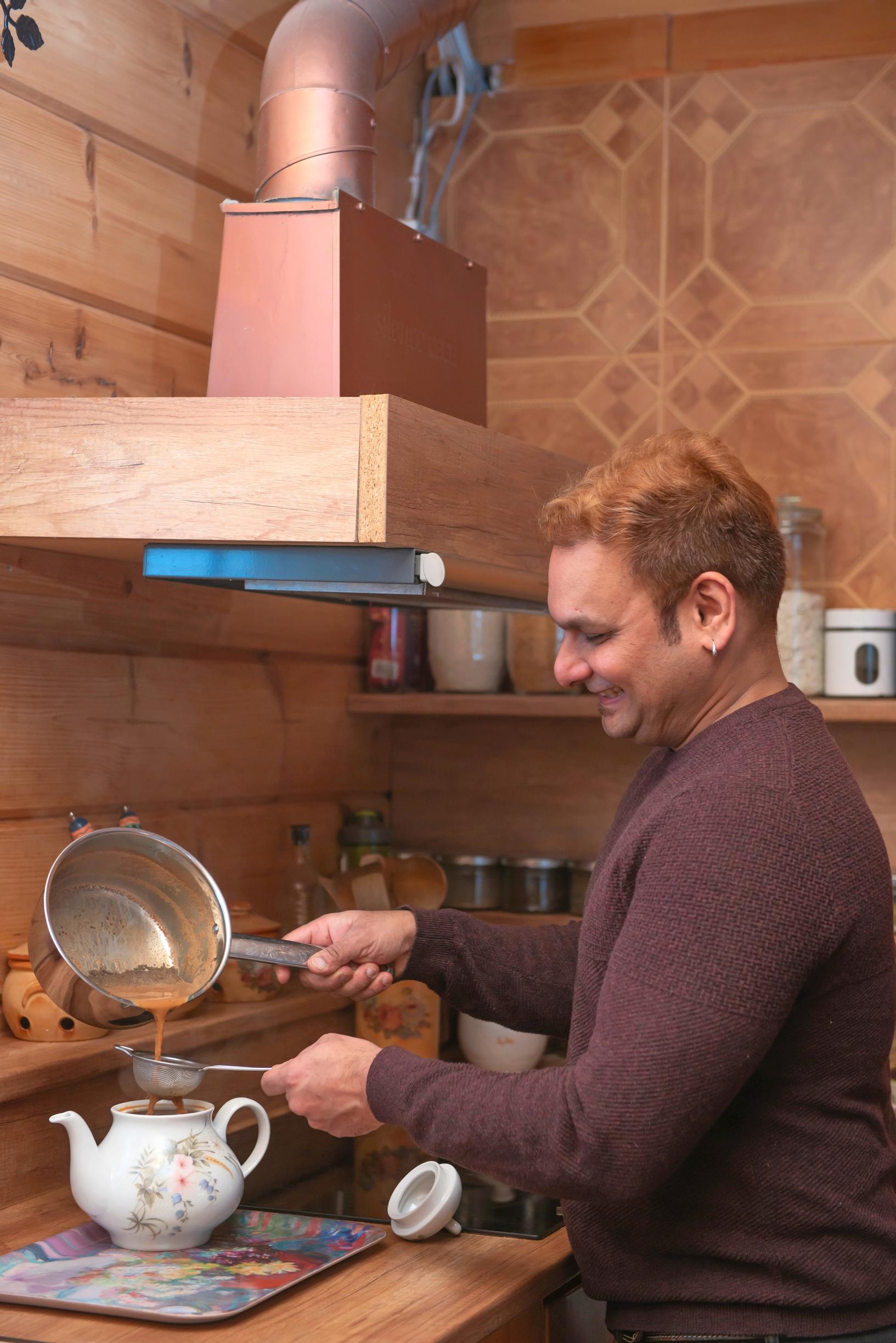 man pours water through a strainer into a teapot