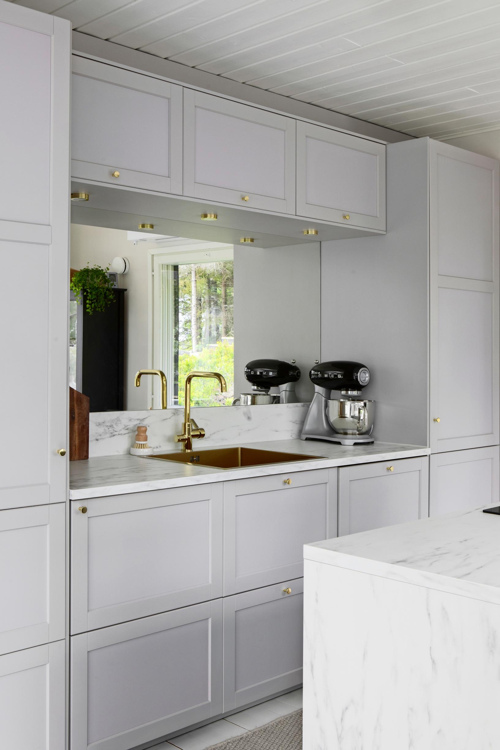 The kitchen cabinets feature framed doors. Three shallow cabinets about 40 cm deep are installed above the backsplash area.