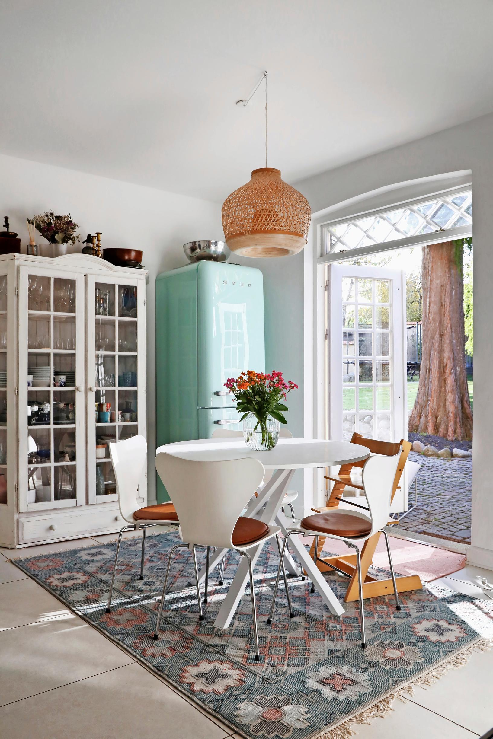 In the everyday dining area, an old china cabinet and Series 7 chairs around a round table, with double doors leading outside