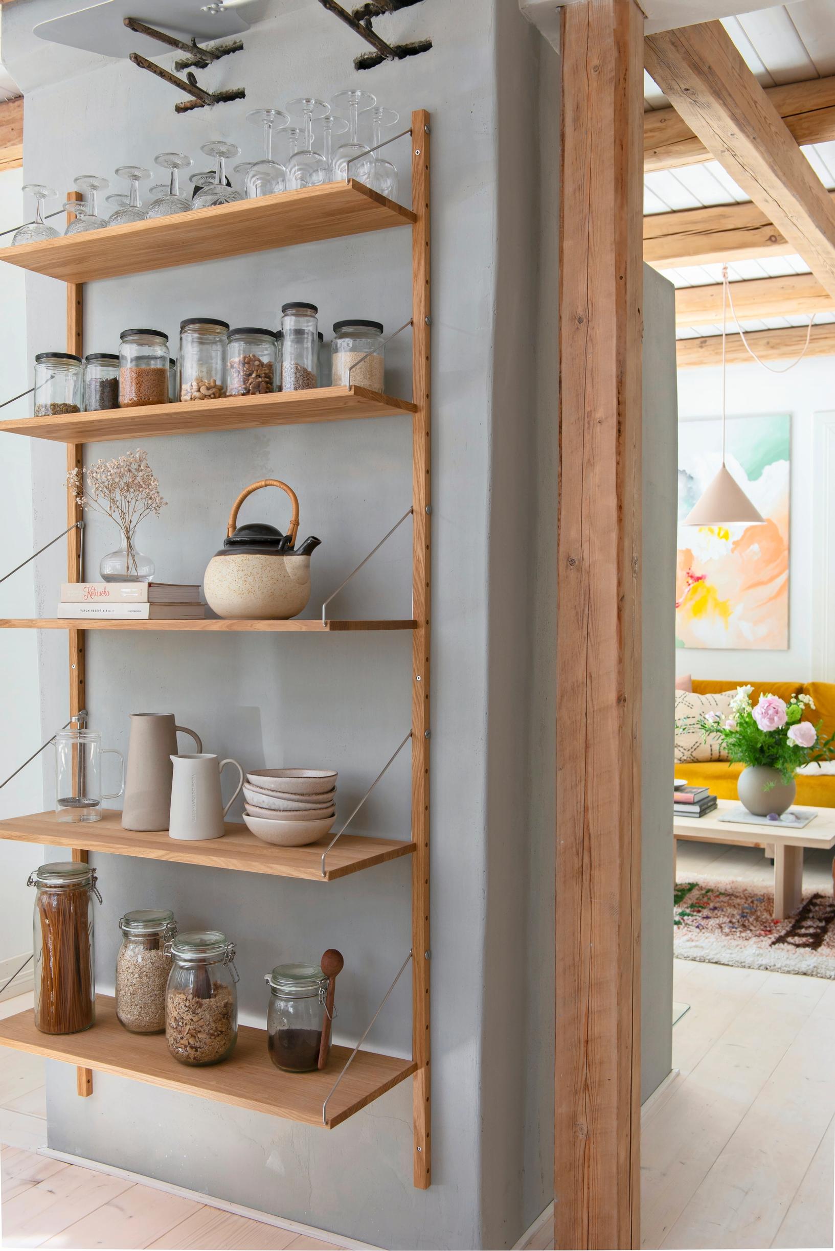 Dishes and utensils on a tall wooden open shelf in the kitchen