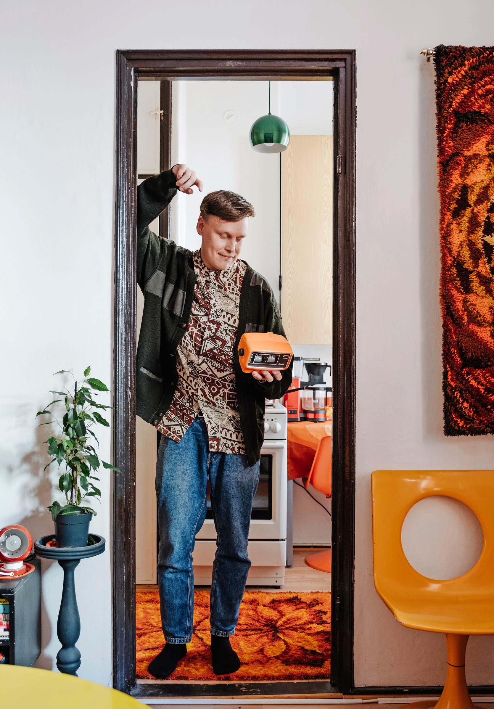Photo of a man standing in the doorway of a retro-style apartment.