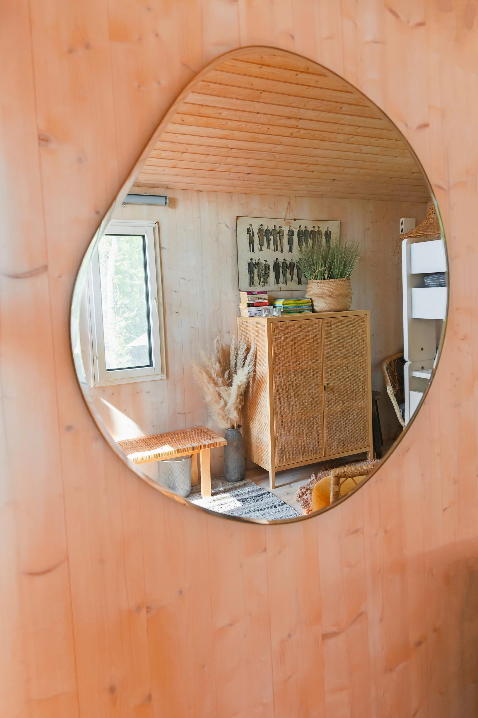 In the mirror on the plank wall, a rattan cabinet is reflected.