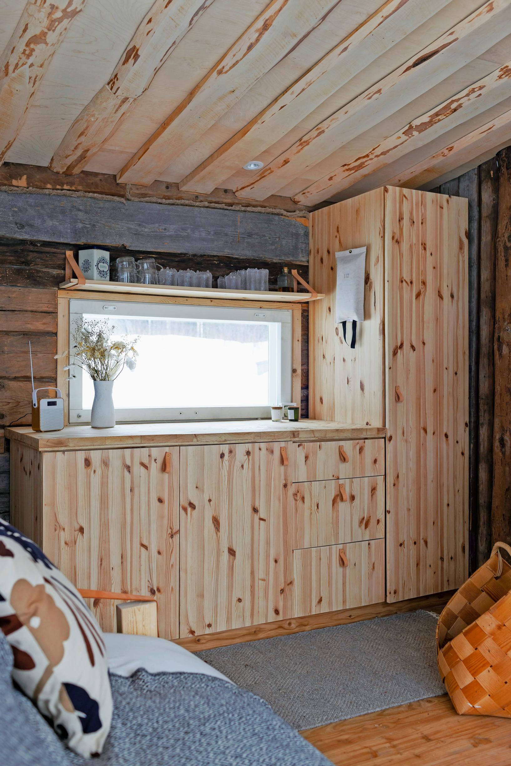 A pine cabinet in front of a window, with a sofa and a woven wooden basket.