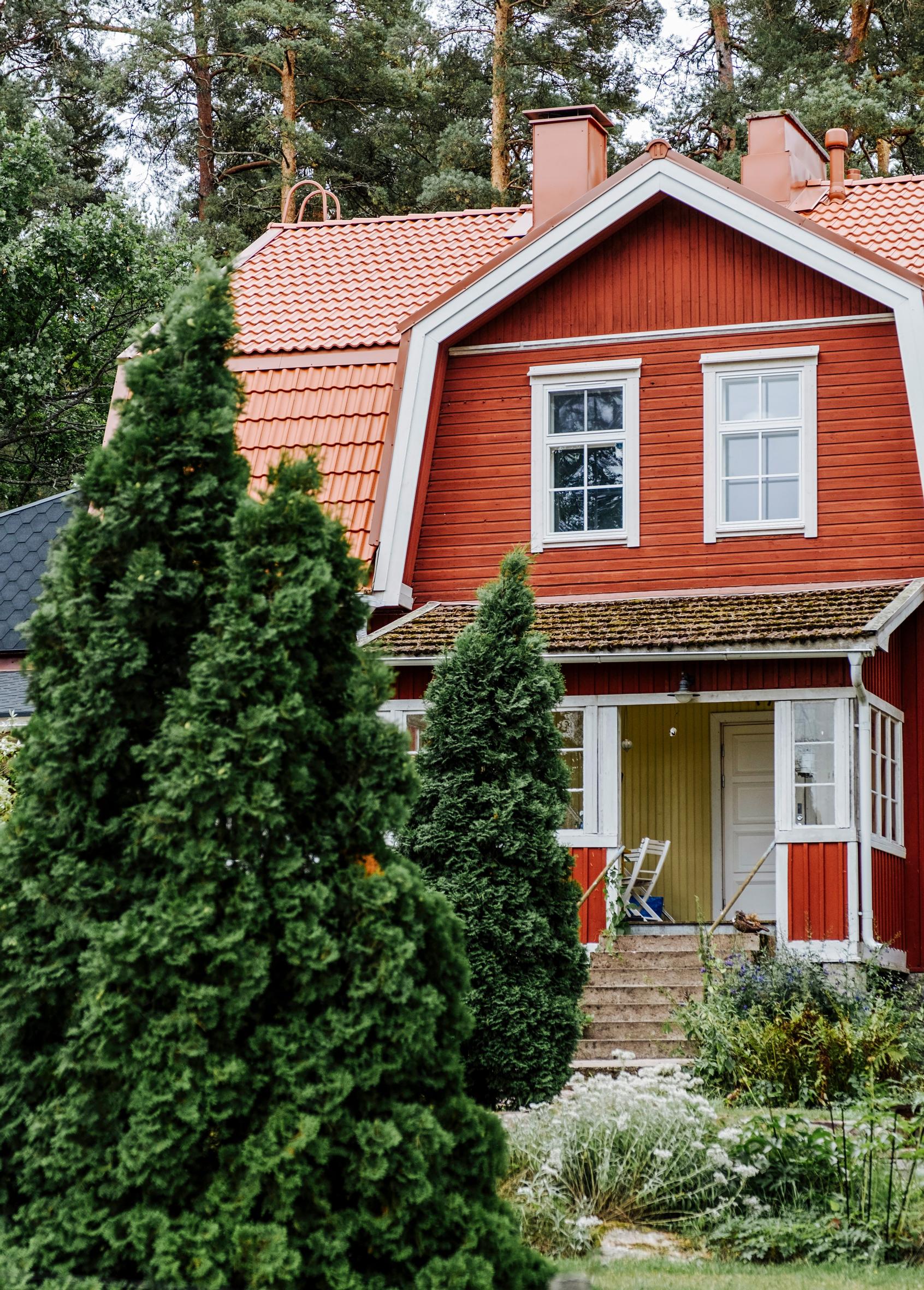 A red wooden house with a mansard roof