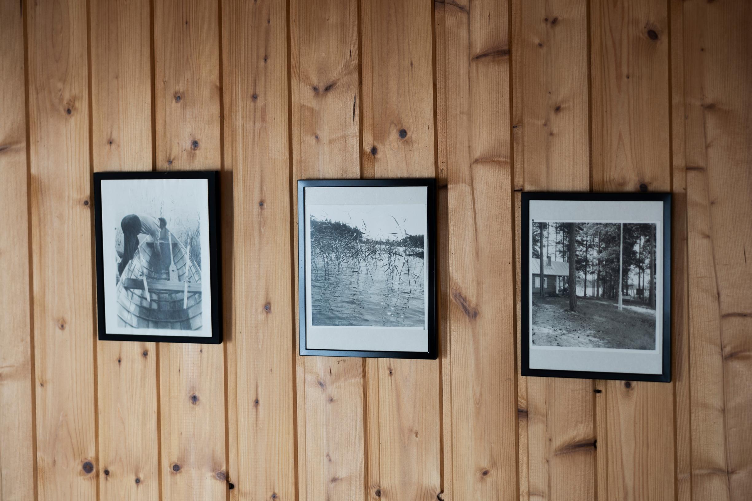Three black-and-white old photographs on the wall in a row, plank wall