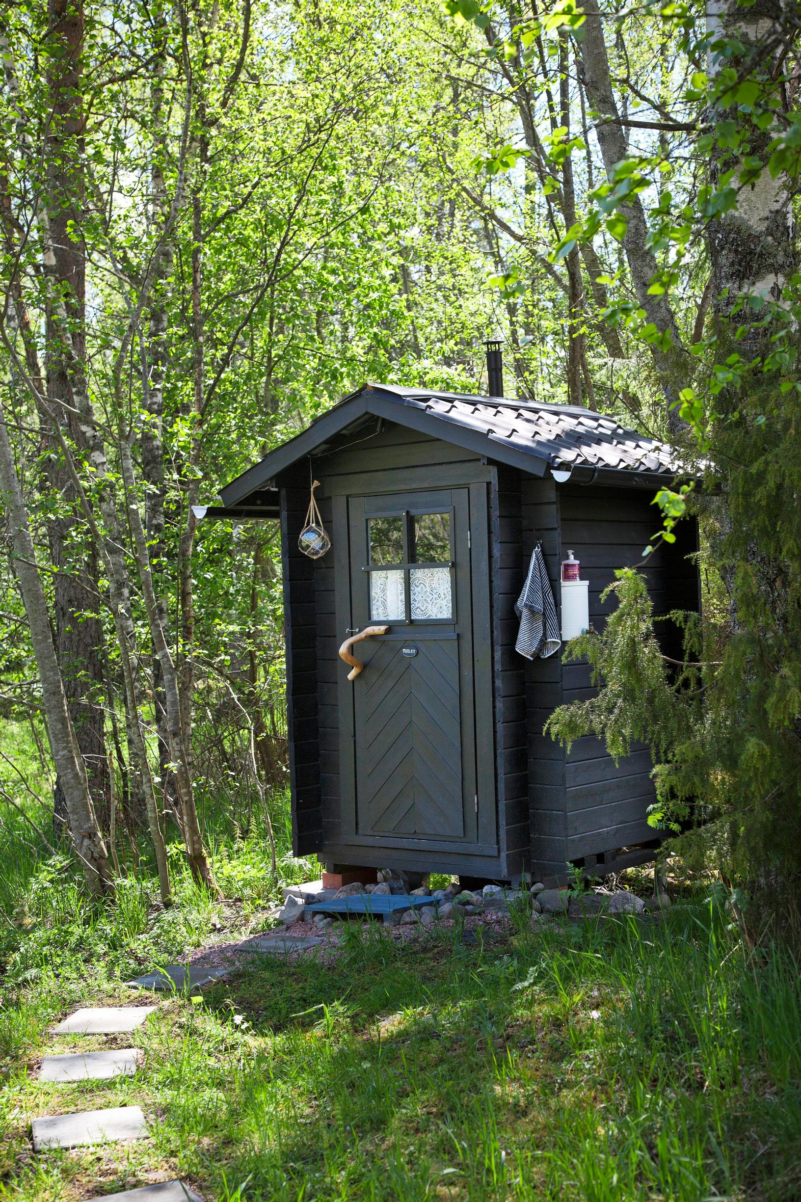 A gray-painted outhouse.