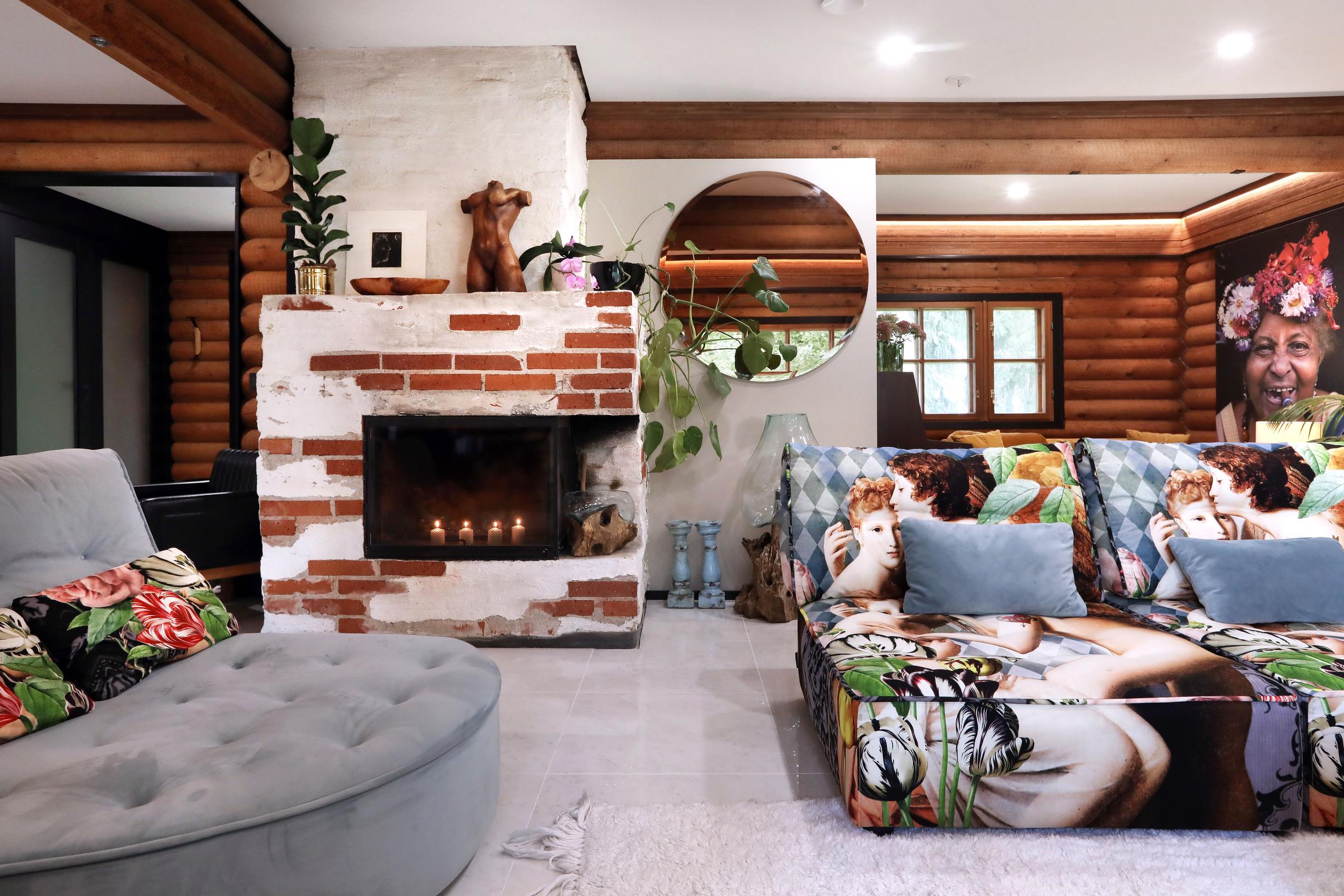 In the living room, there’s a colorful sofa and a partially brick-covered fireplace filled with candles