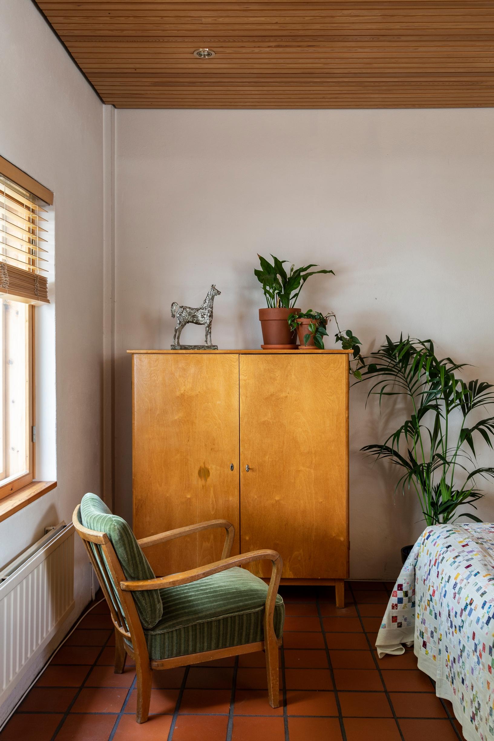 An old linen cabinet and armchair, houseplants, and a bronze horse sculpture