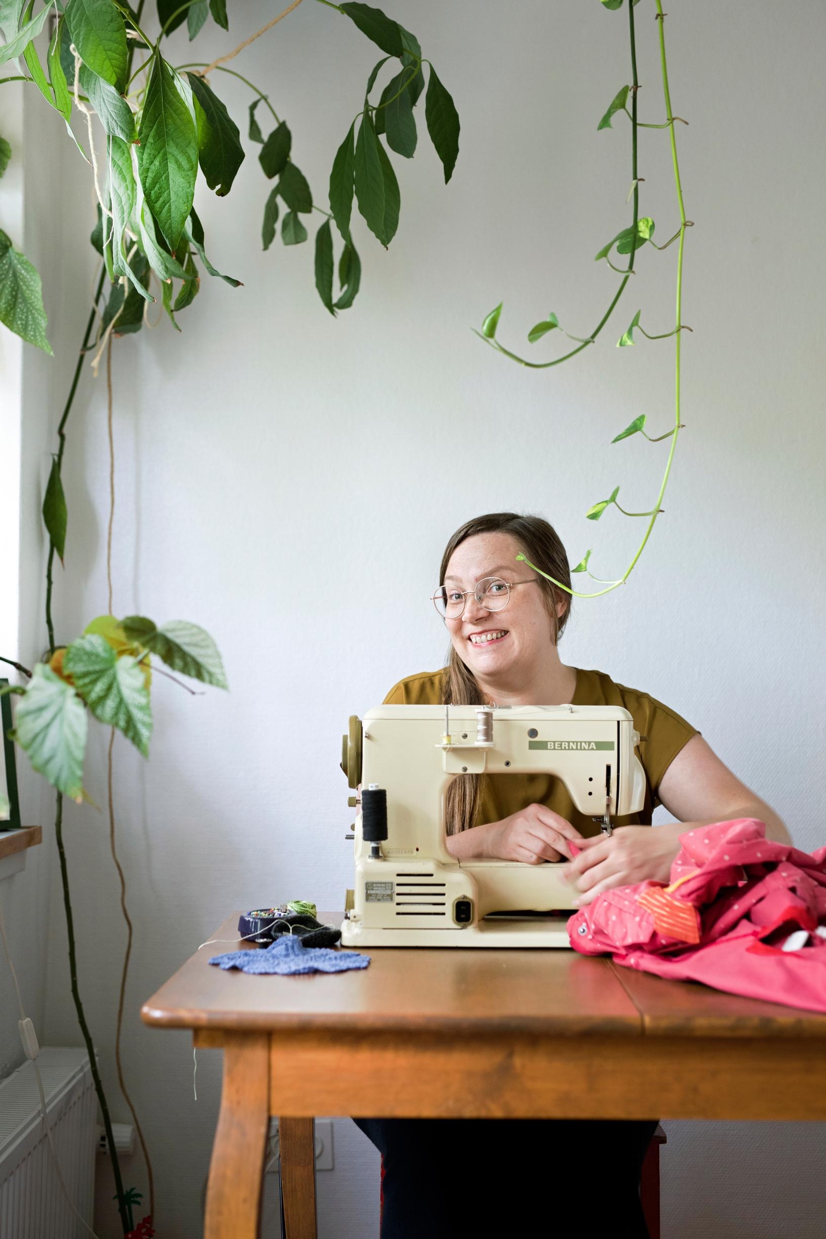 A woman sits at a sewing machine