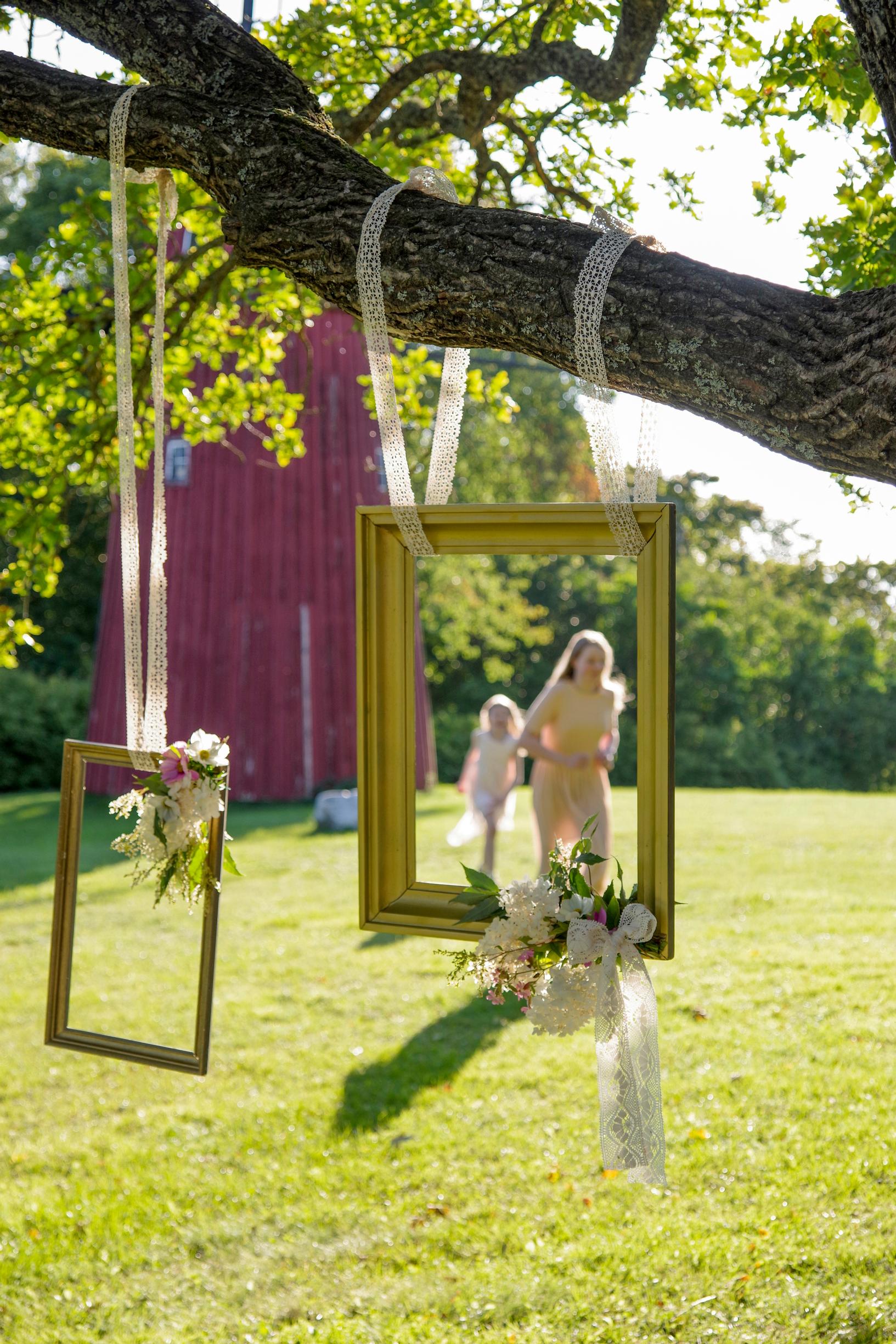 Picture frames hung from a tree branch serve as photo frames at a party.