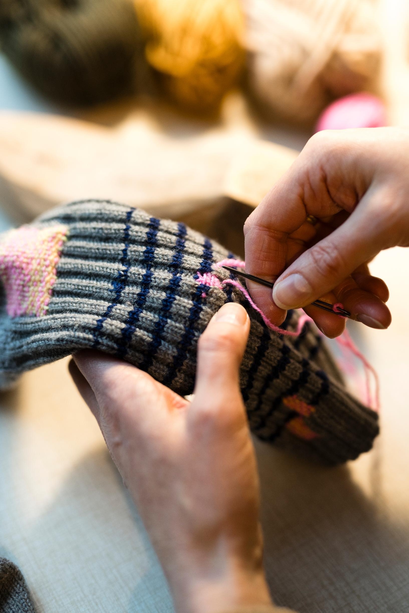 Minttu darning a wool sock.