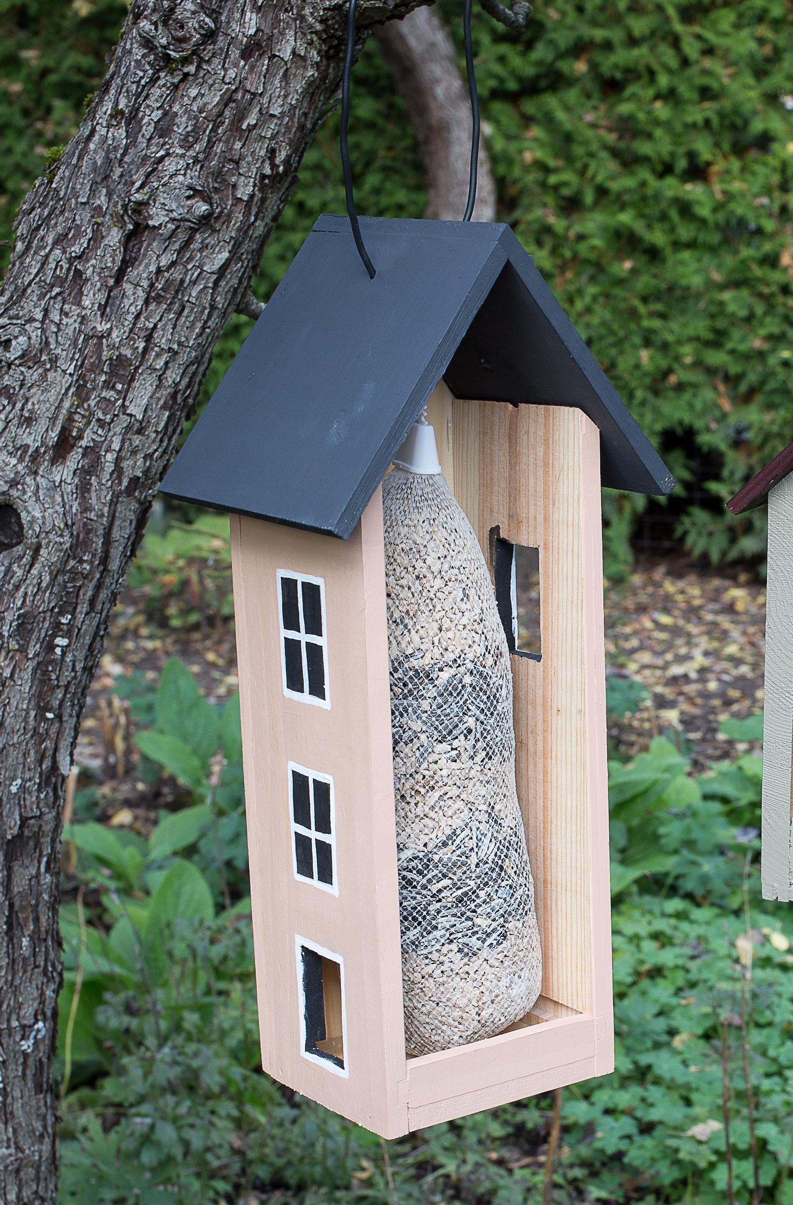 Bird feeder house attached to a tree from behind