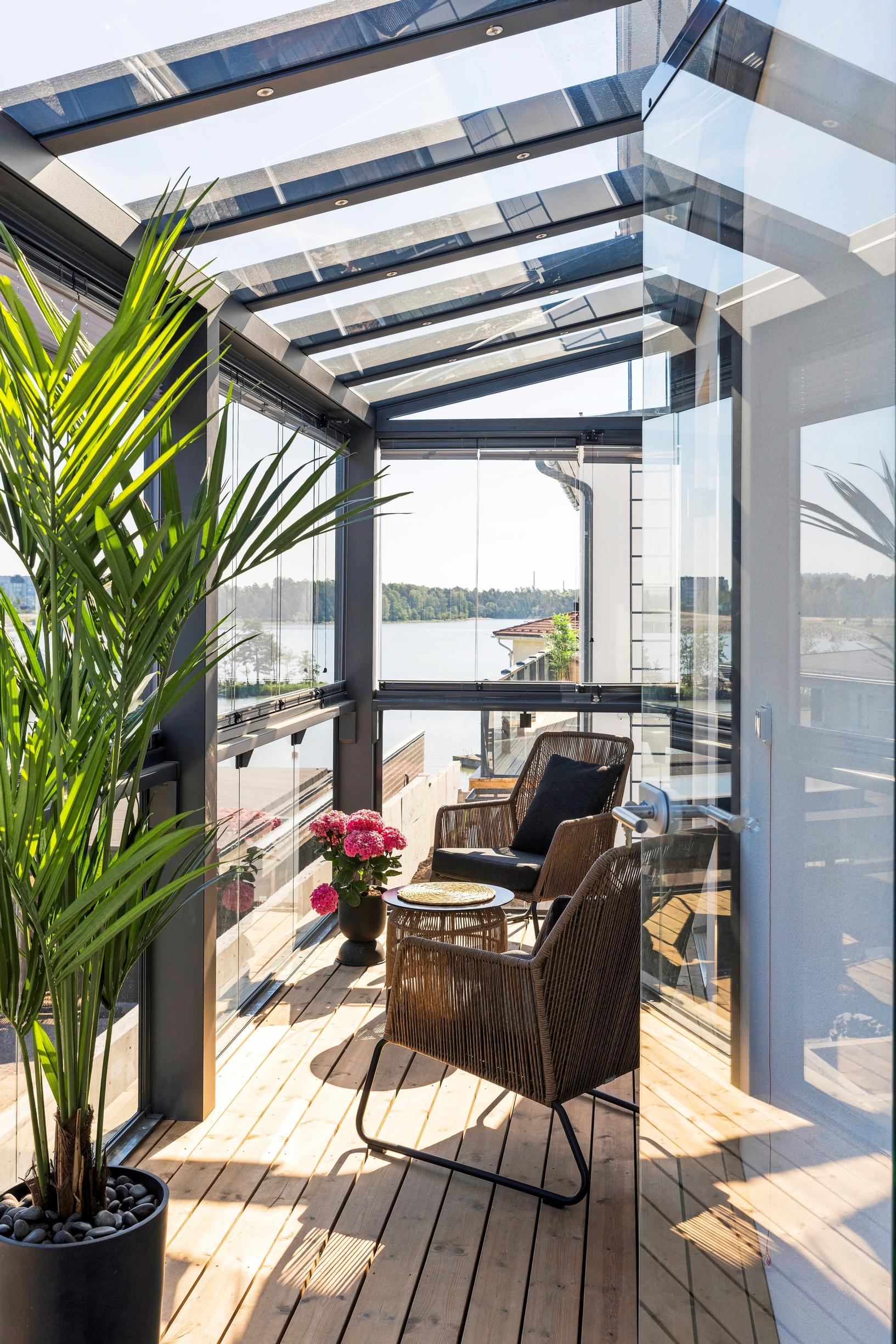 A narrow glazed balcony furnished with poly rattan chairs