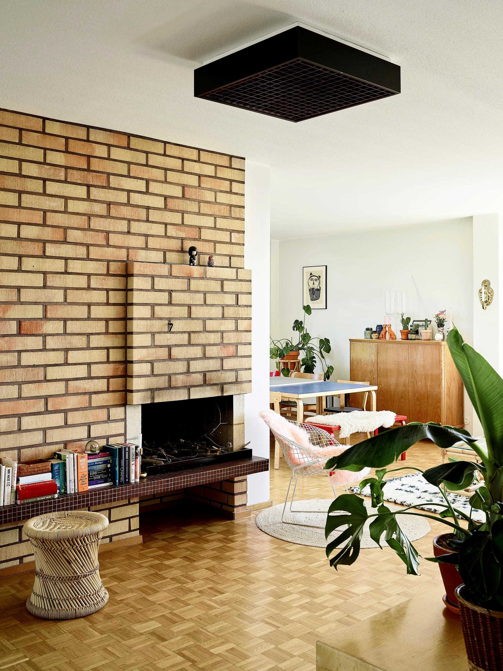 A yellow brick open fireplace in the living room with a mosaic parquet floor.