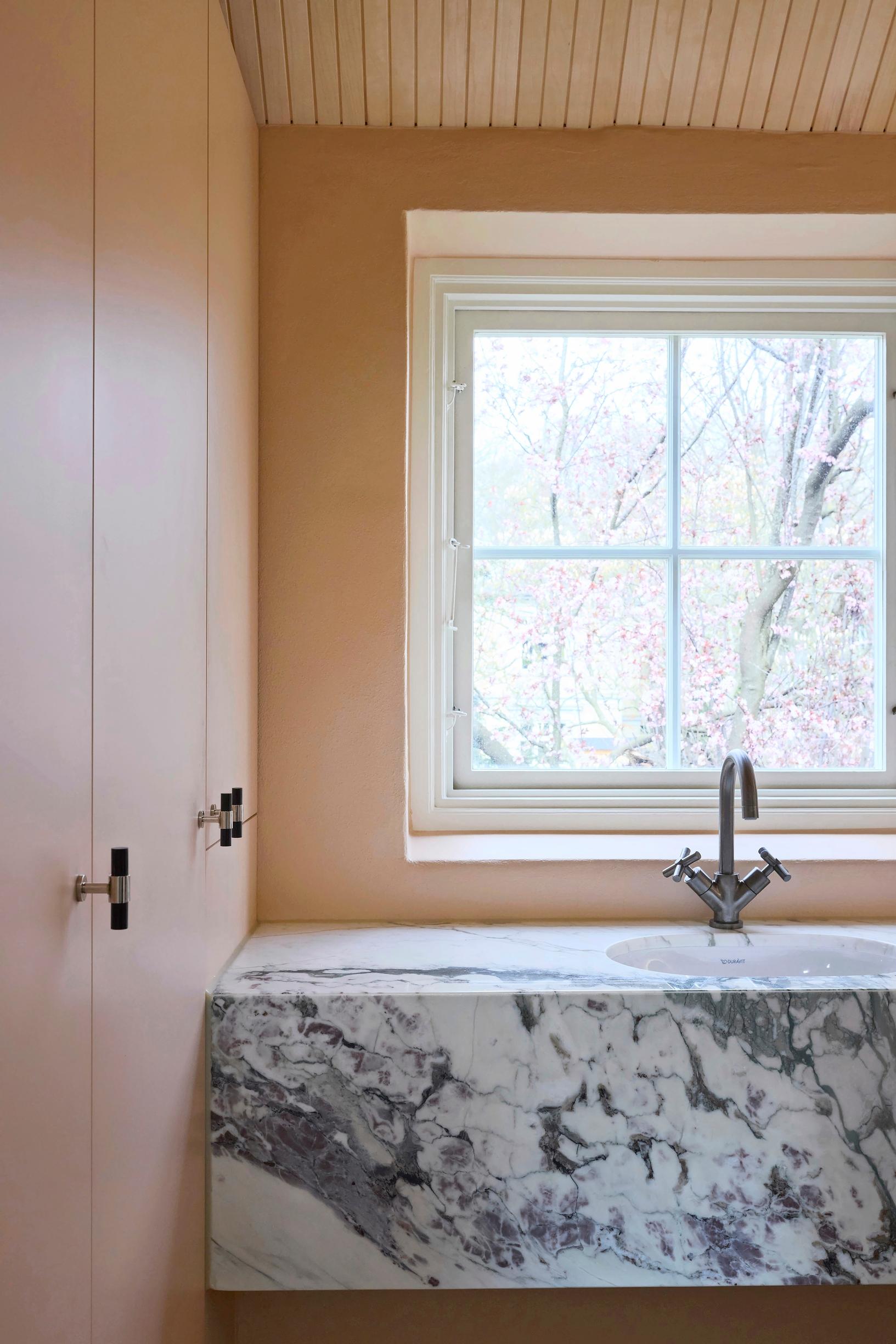A peach-colored cabinet and a marble countertop in the bathroom