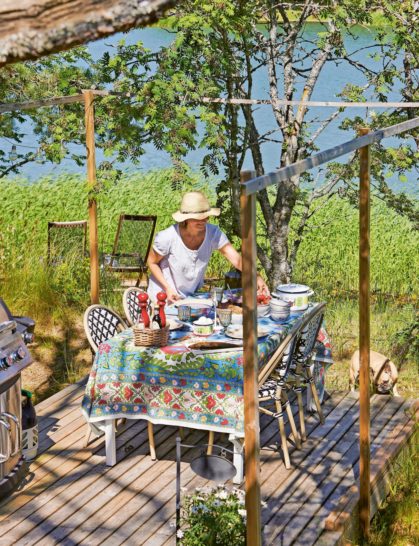 Heli sets the table outdoors under the pergola, reeds and the sea in the background