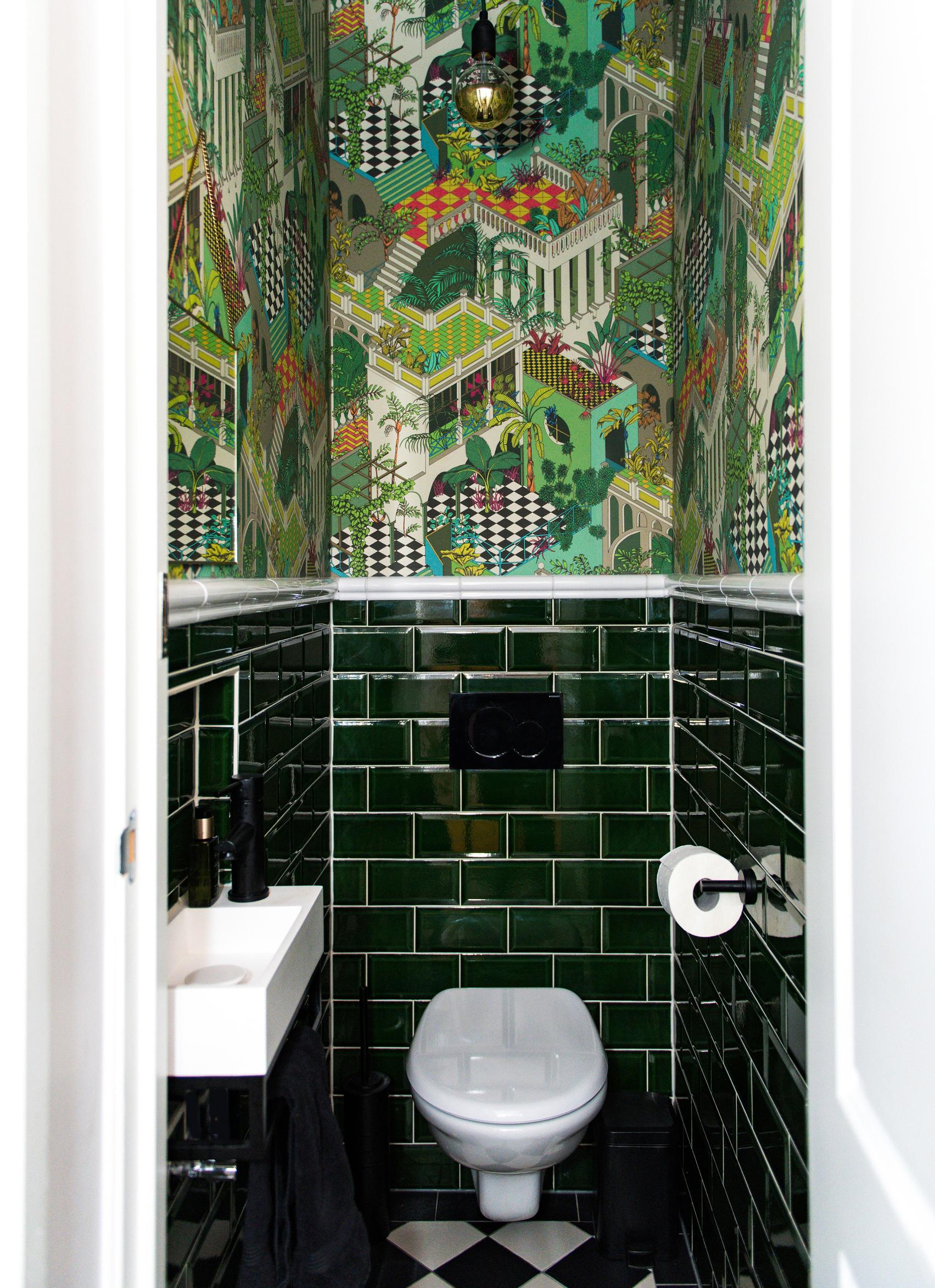 The bathroom features green subway tiles and a green cityscape wallpaper on the upper part of the wall.