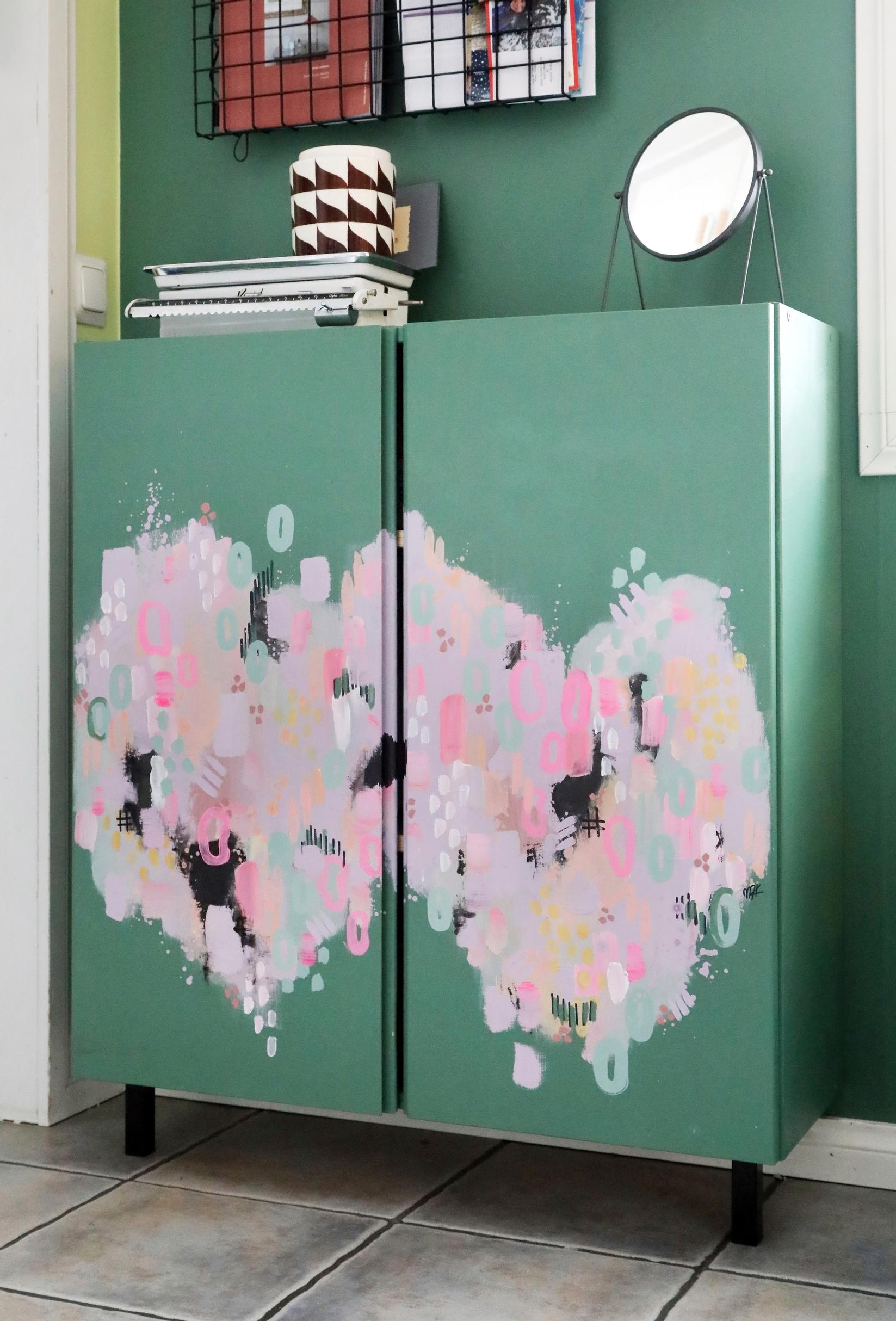 A cabinet painted the same color as the wall, with large hearts on the doors.