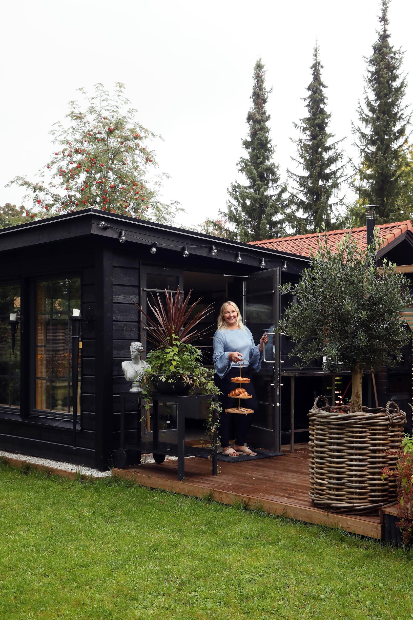 A dark wooden building with a flat roof and a large deck.