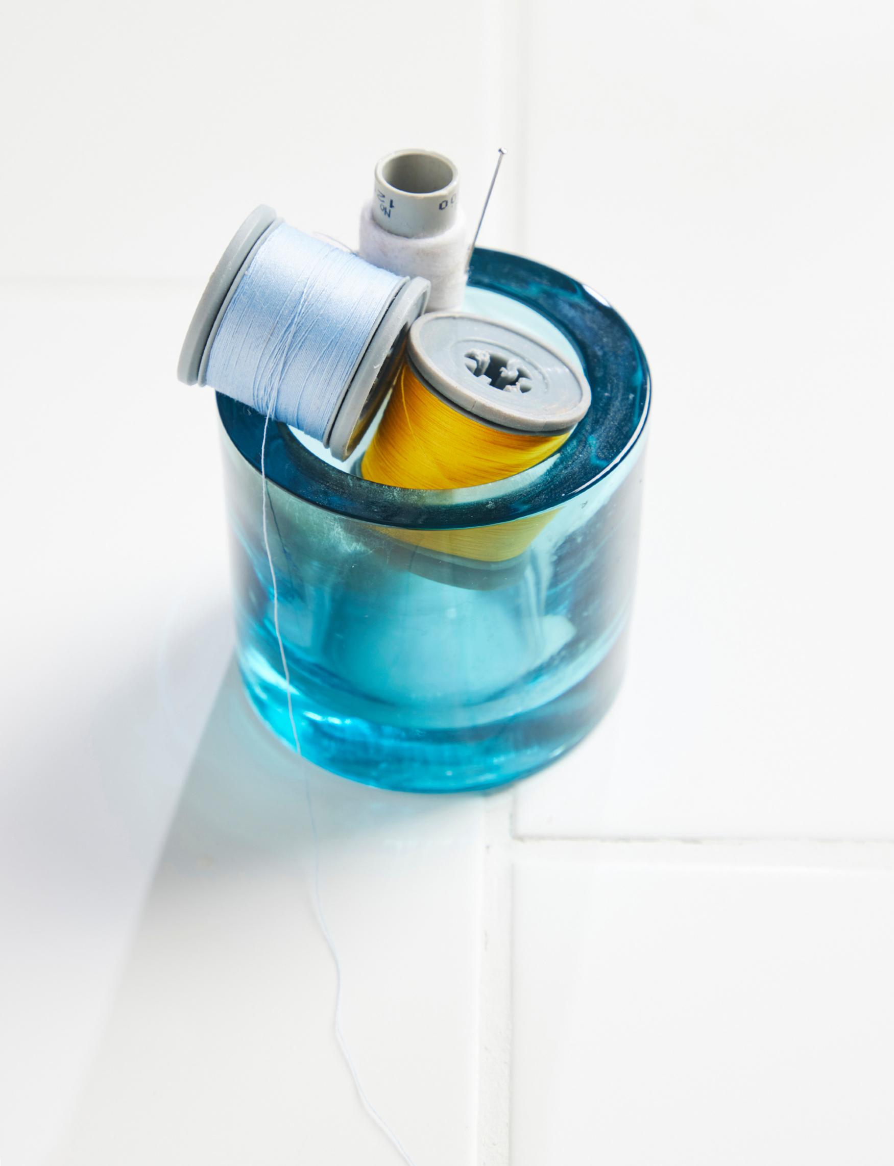 A Kivi tea light holder filled with spools of thread.