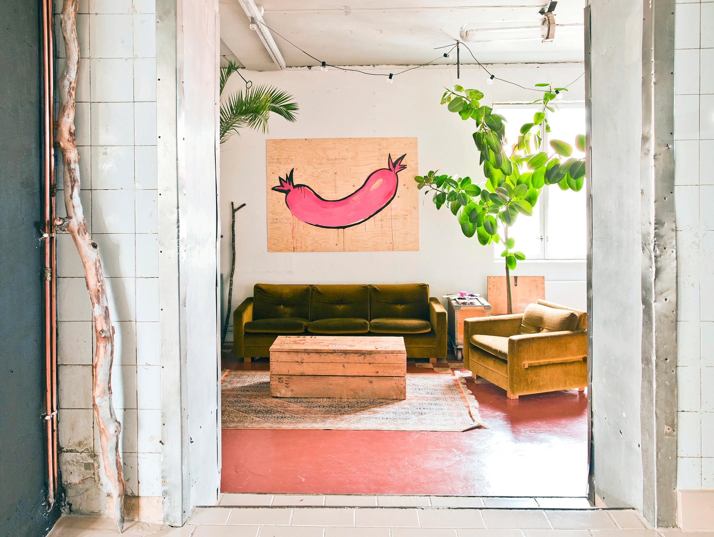 Pink sausage artwork above the velvet sofa