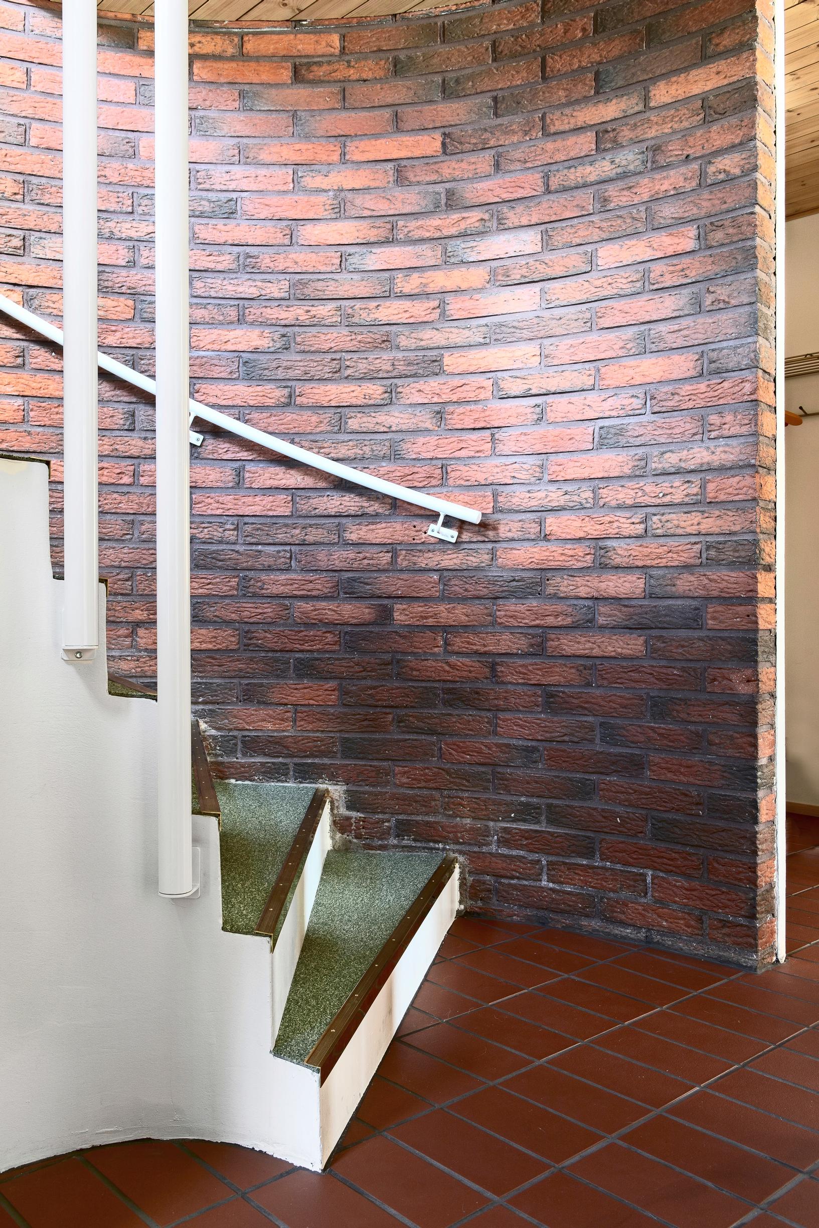 A curved brick wall serves as the backdrop to the sweeping staircase.