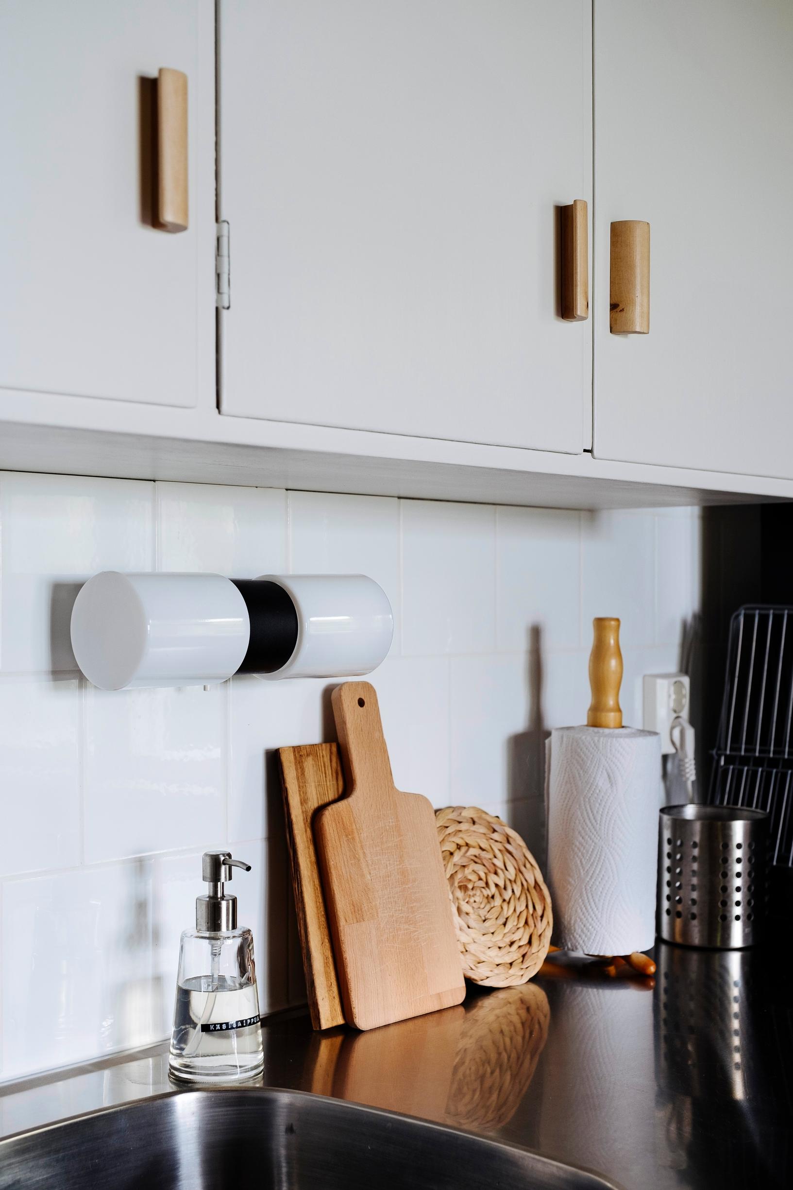 1950s-style kitchen cabinets and a wall lamp above a stainless steel sink